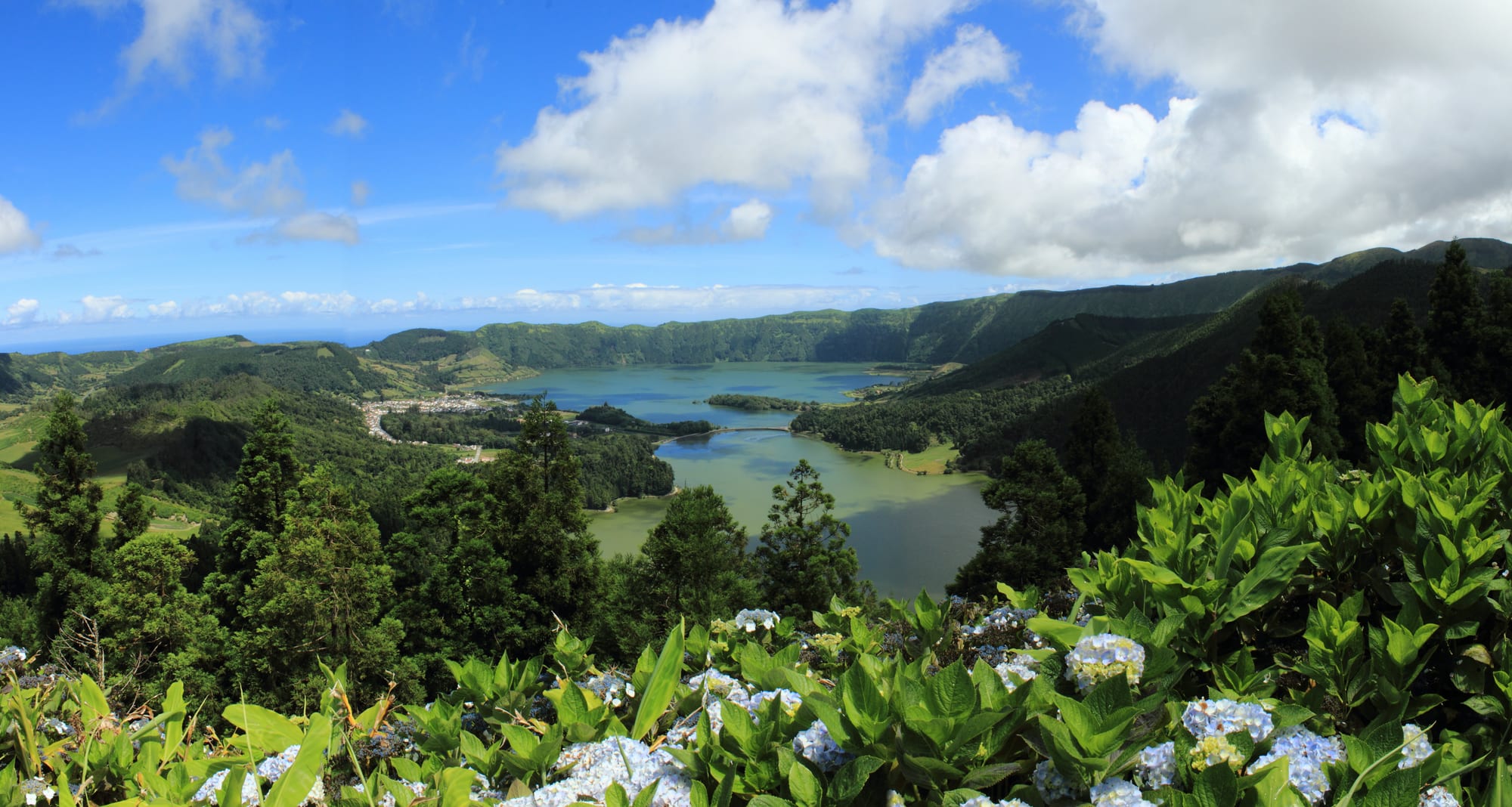 Two joined crater lakes, one blue and one green, in a huge caldera ringed by farmland