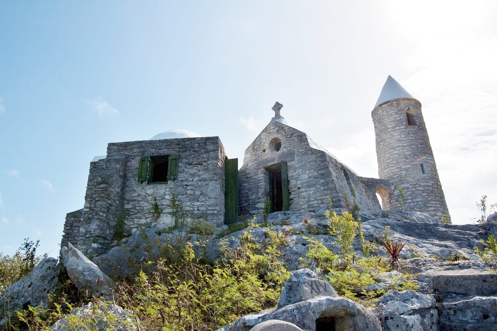 A tiny stone monastery with miniature towers on a bare hilltop