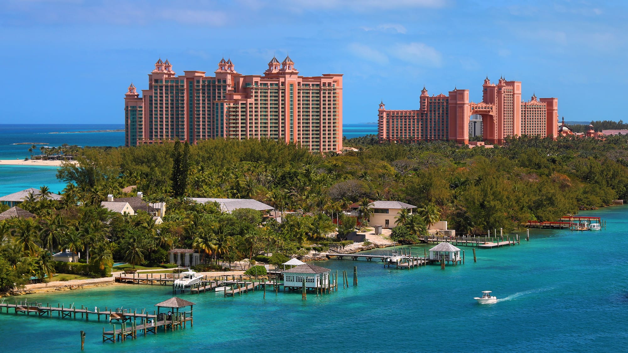 A vast pink-and-cream resort complex with towers and a bridge, on a low island