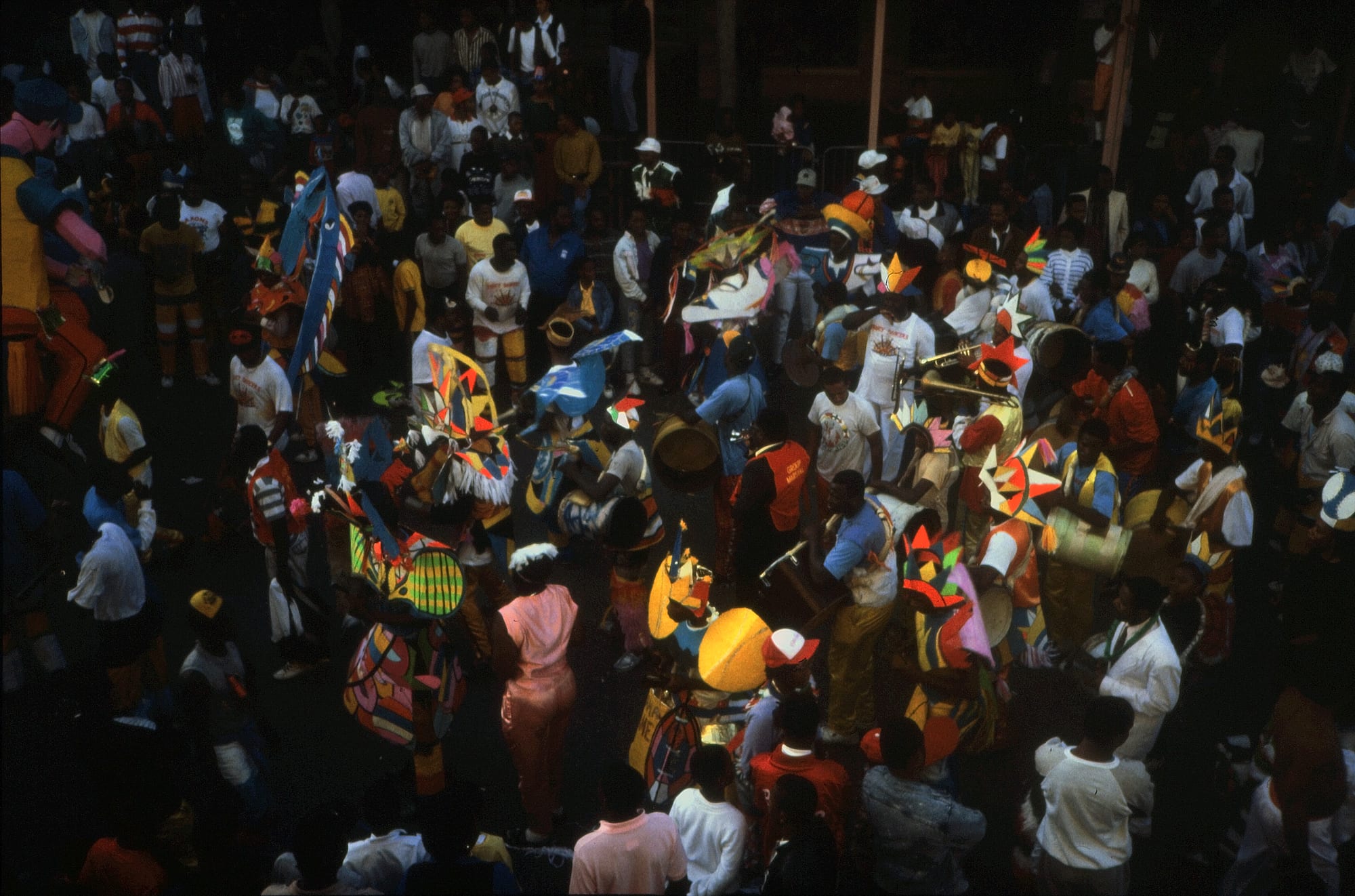Masqueraders in tall, brightly coloured crepe-paper costumes parading in a street