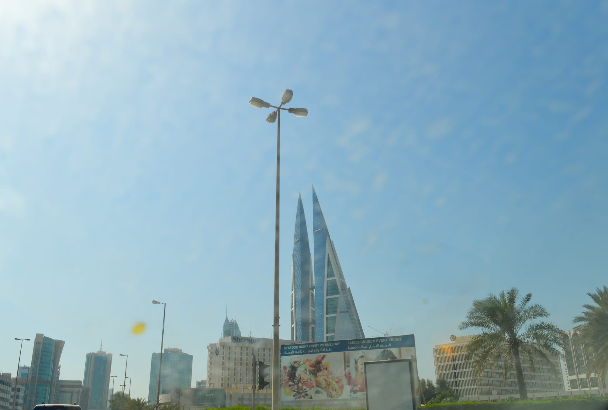 Twin sail-shaped skyscrapers linked by three bridges, each carrying a wind turbine