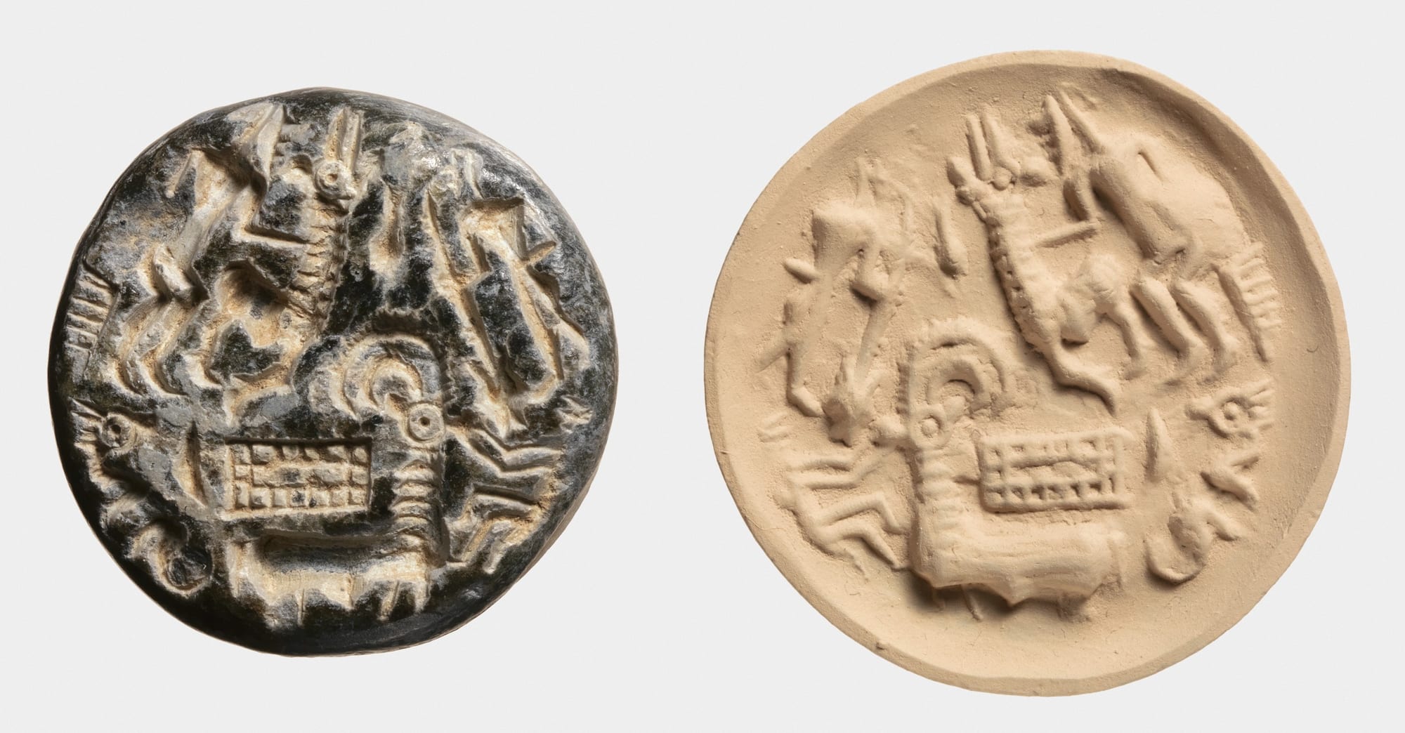 A small round dark stone seal carved with goats and figures, beside its impression pressed into pale clay