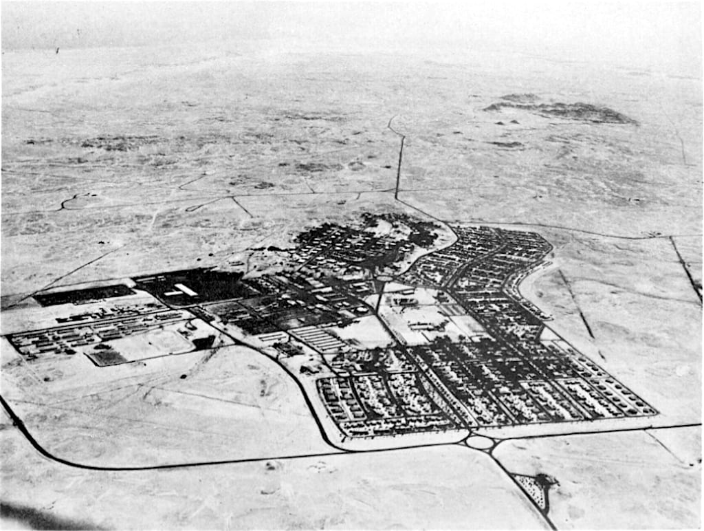 A 1950s aerial photograph of a planned town of bungalows and gardens laid out in the desert