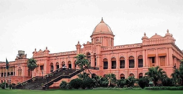 A large pink two-storey palace with a central dome and wide steps down to a river