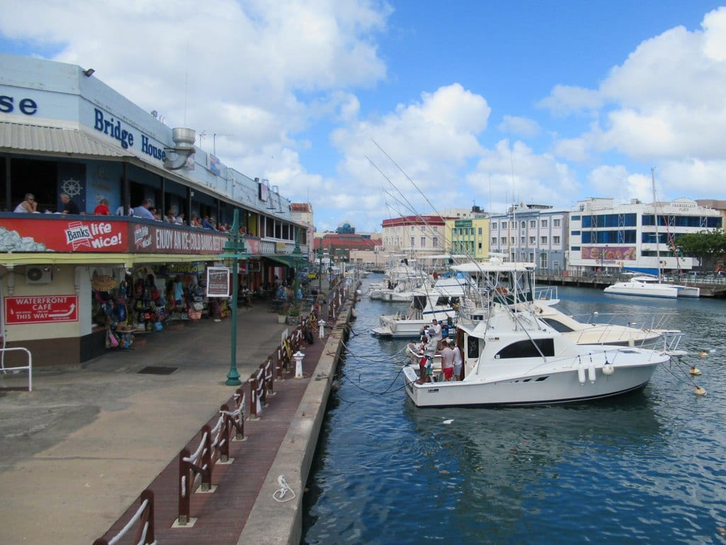 A small harbour inlet full of boats, lined with colonial buildings and a bridge