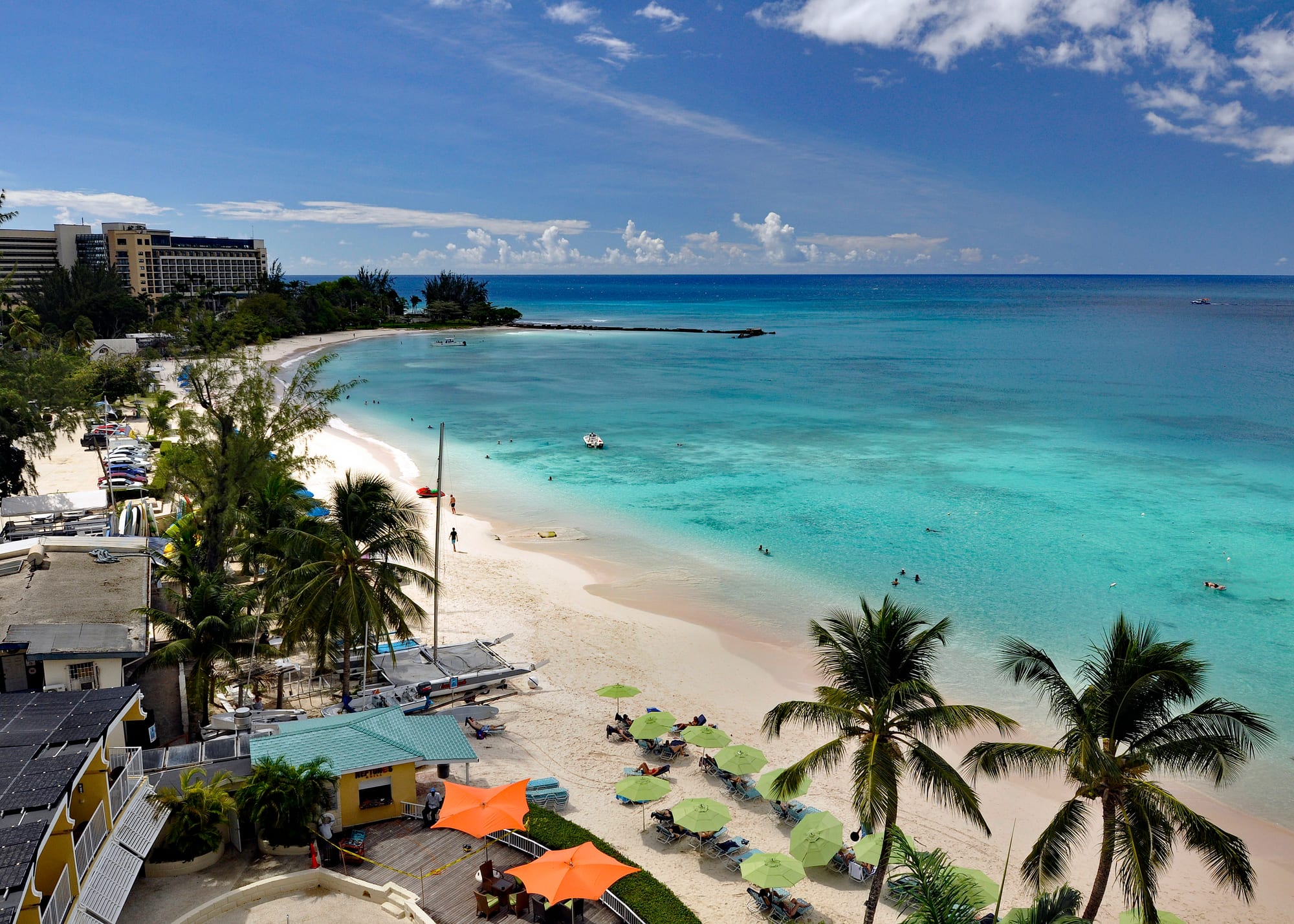 A calm bay of clear turquoise water and pale sand, boats moored offshore