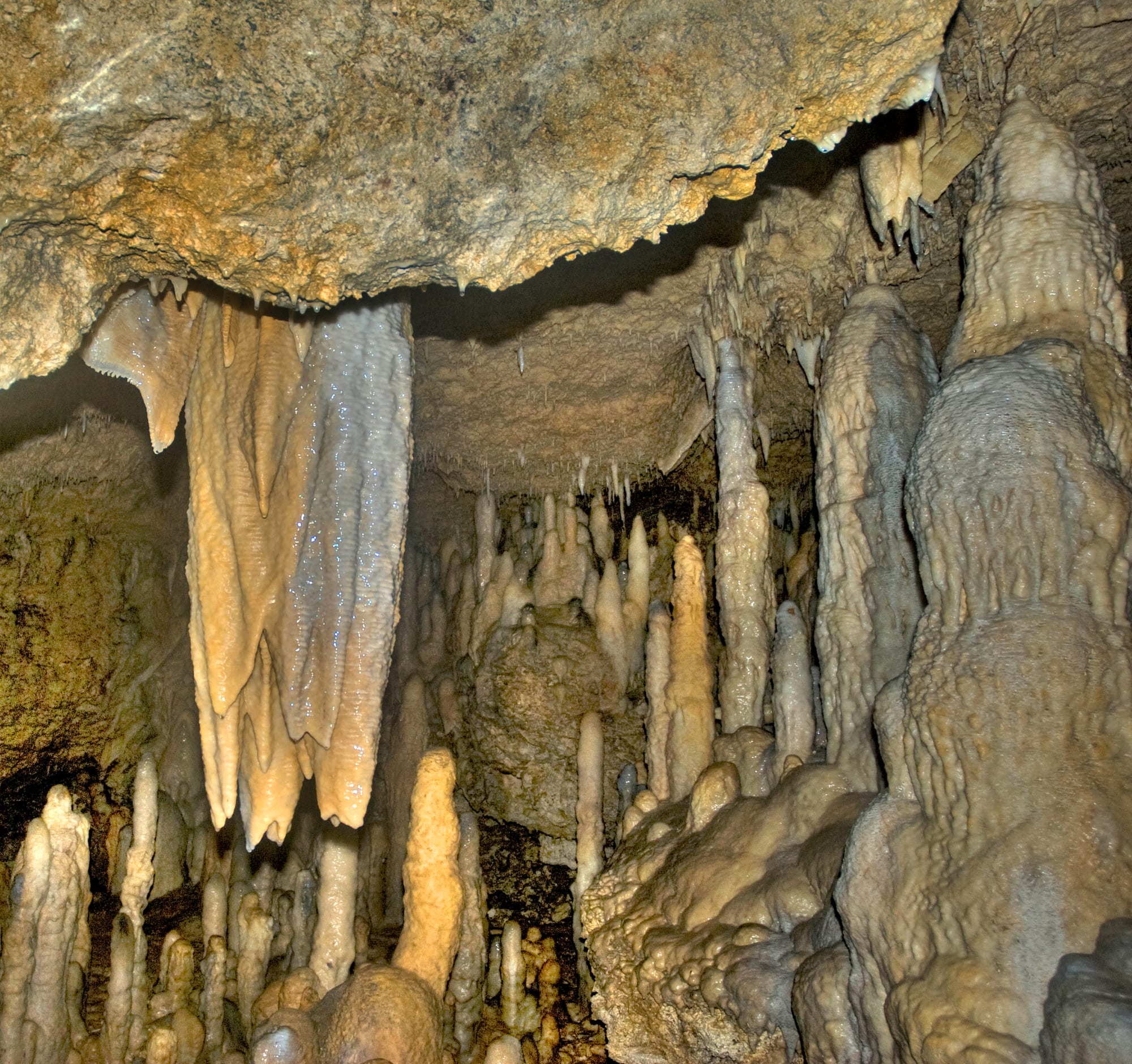 A large limestone cavern with flowstone, stalactites, and a pale green pool