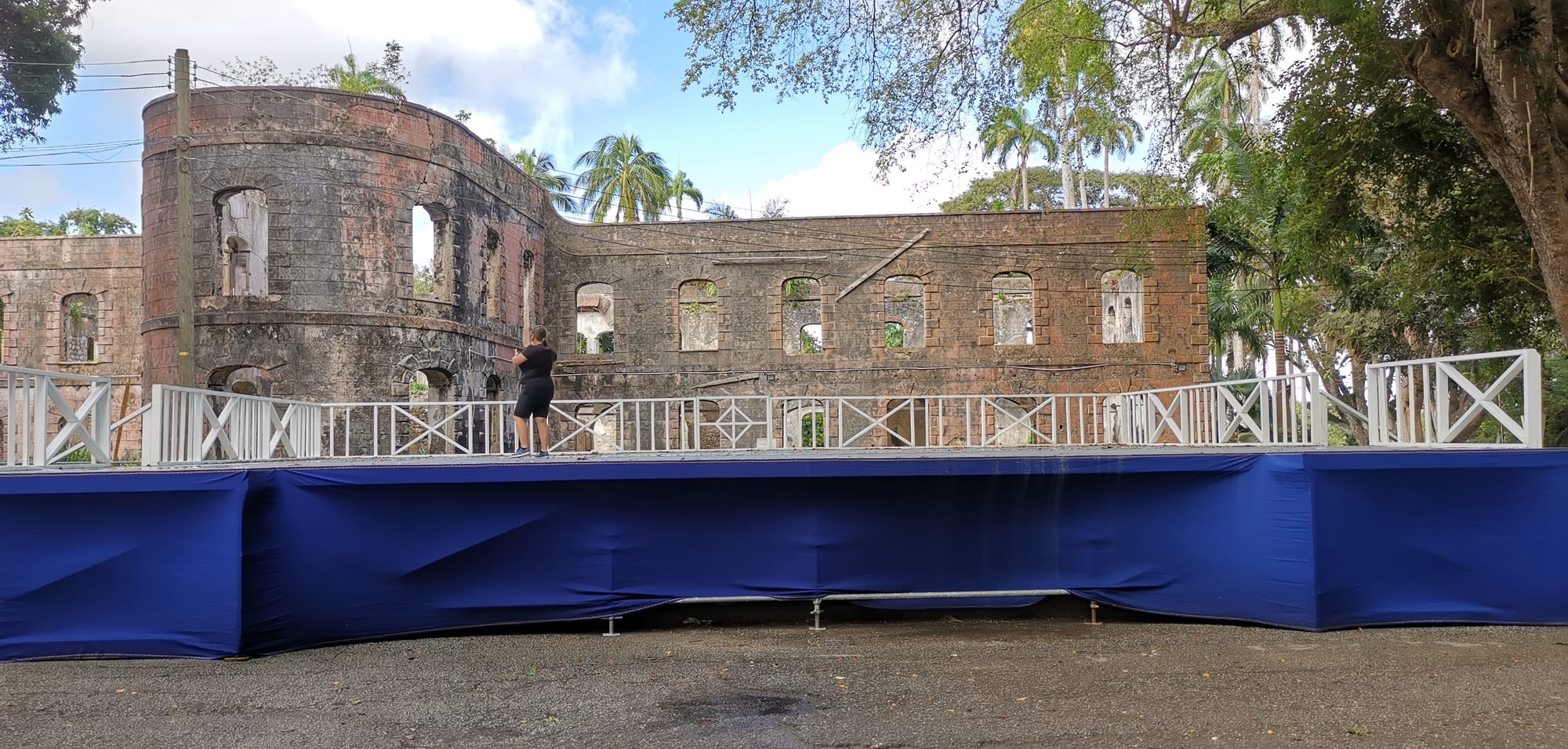 The roofless stone shell of a grand great house among tall mahogany trees