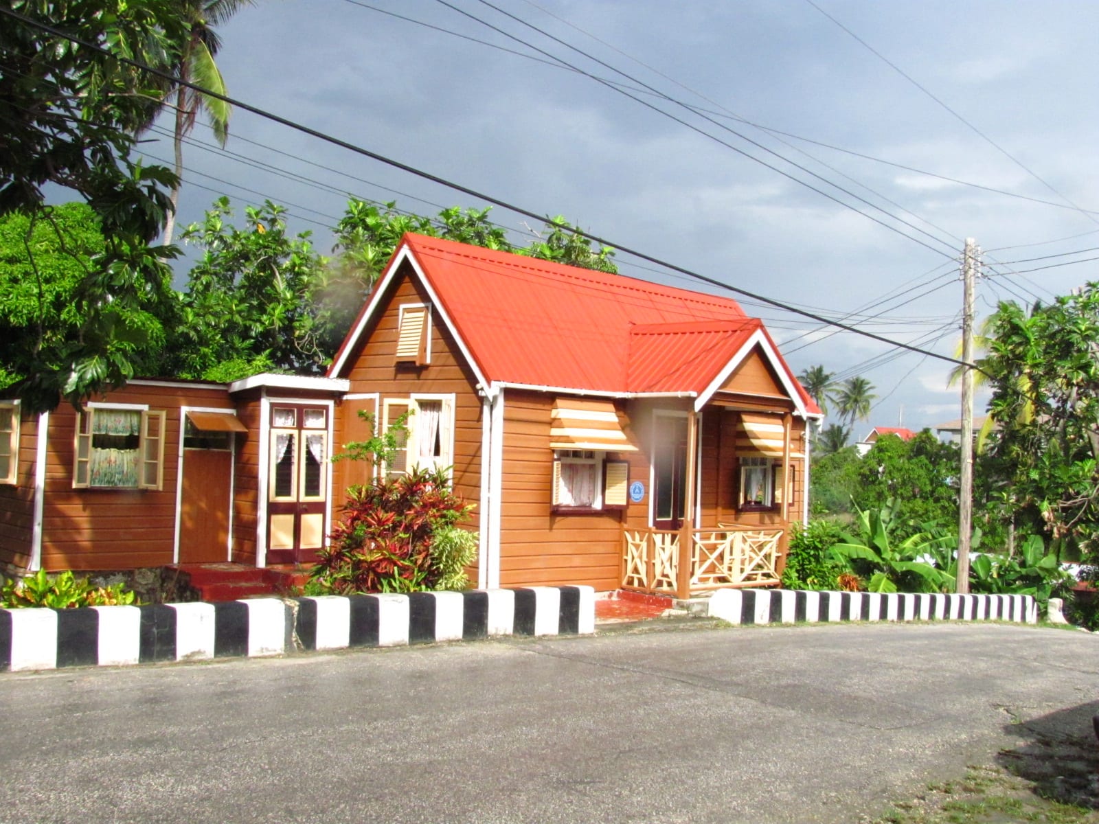 A small brightly painted wooden house with a steep roof and symmetrical windows, raised on blocks