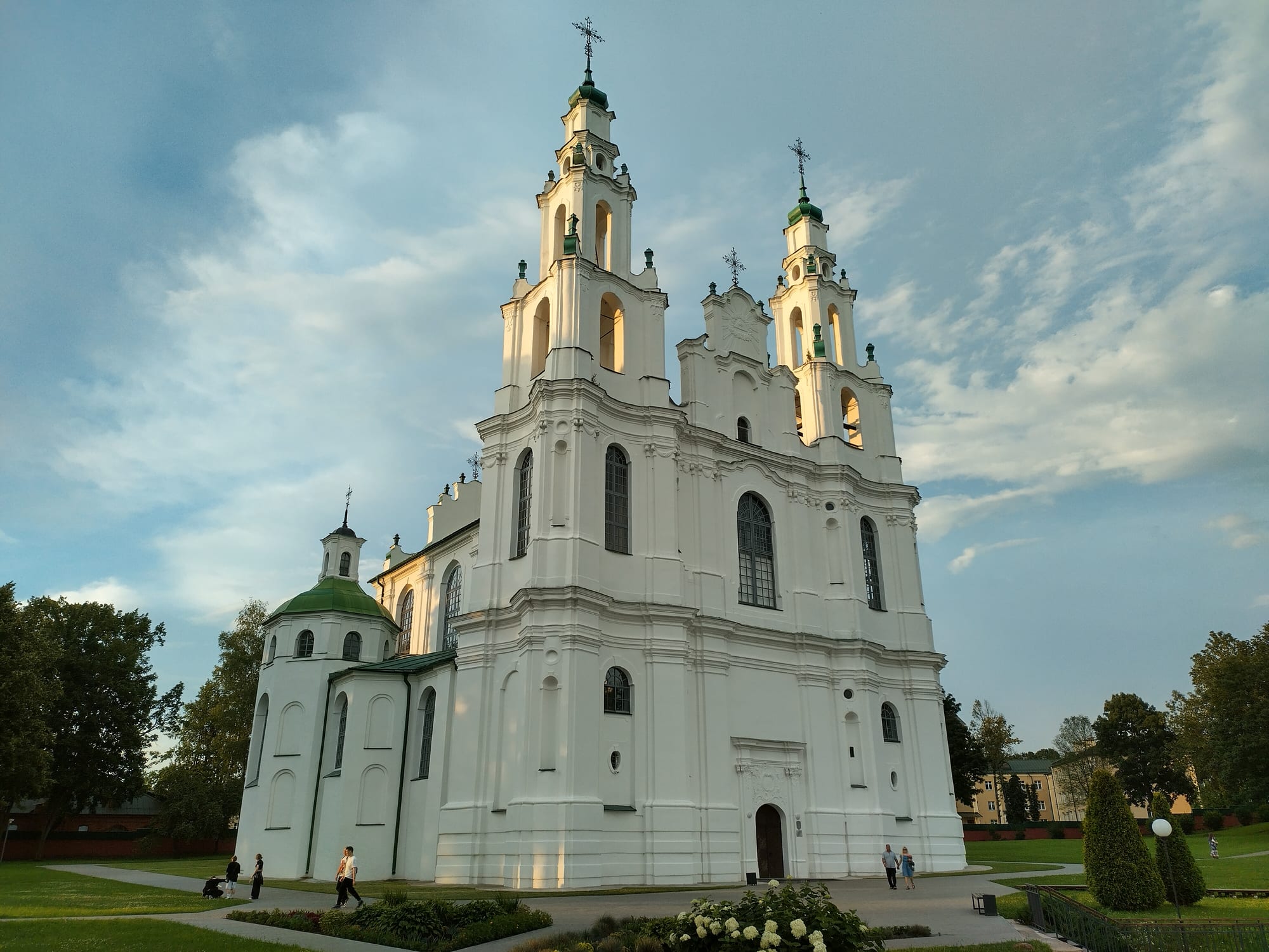 A white Baroque church with two towers on a bluff above a river