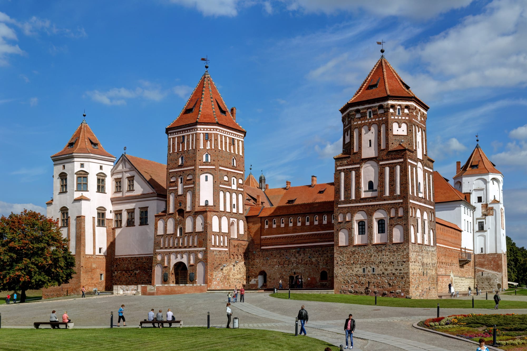 A brick castle courtyard enclosed by tall towers and arcaded palace ranges