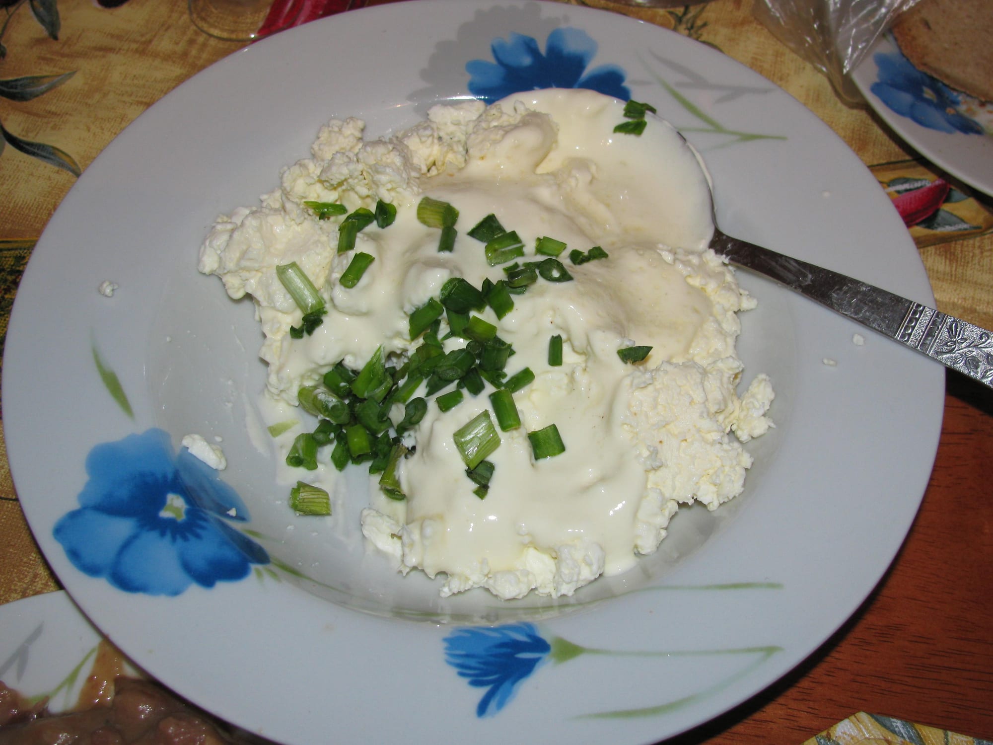A bowl of thick, dark stew with visible pieces of meat, next to a smaller dish of sour cream