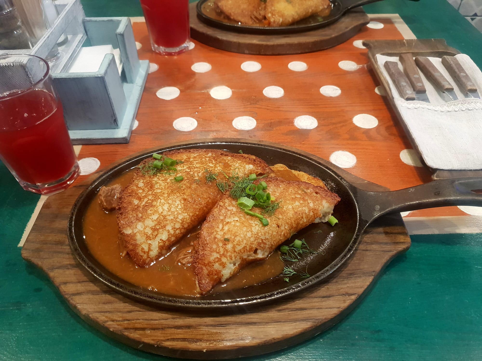 A plate of golden-brown potato pancakes topped with sour cream