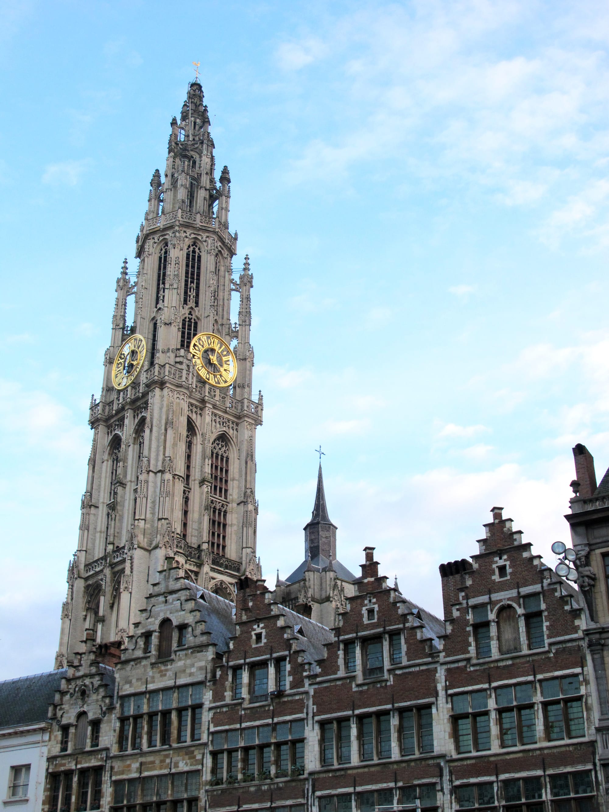 A tall Gothic cathedral spire rising above the gabled guild houses of a market square