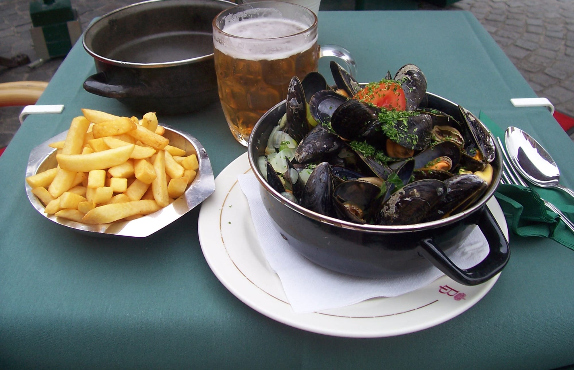A large black pot of steamed mussels beside a cone-shaped serving of golden fries