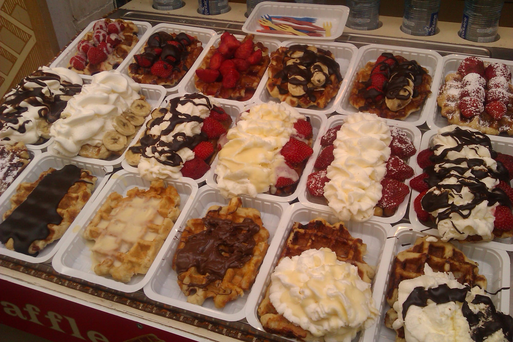 A street food stand selling waffles, near a well-known Brussels landmark