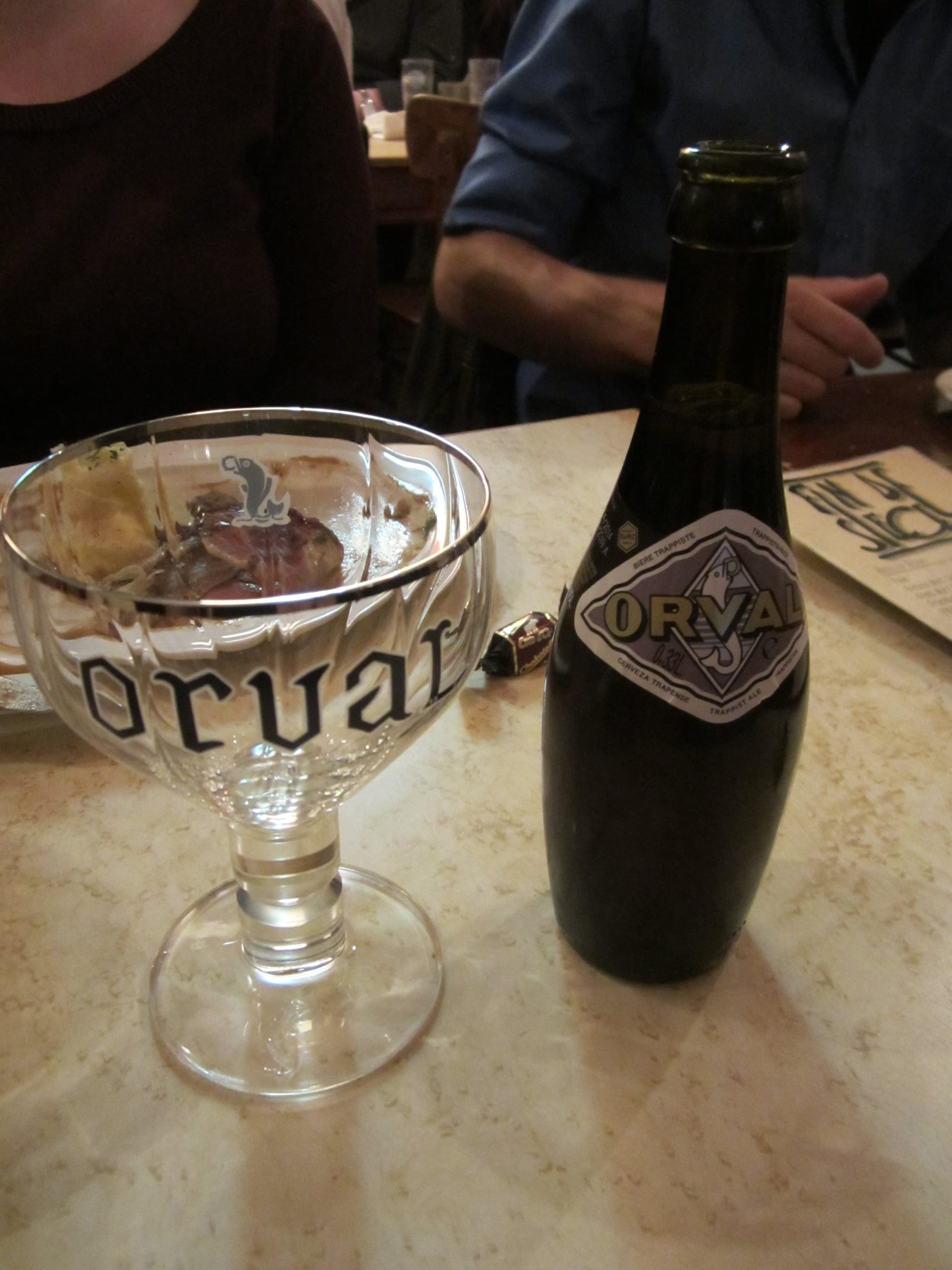 A bottle of Orval Trappist beer next to its distinctive bulb-shaped glass