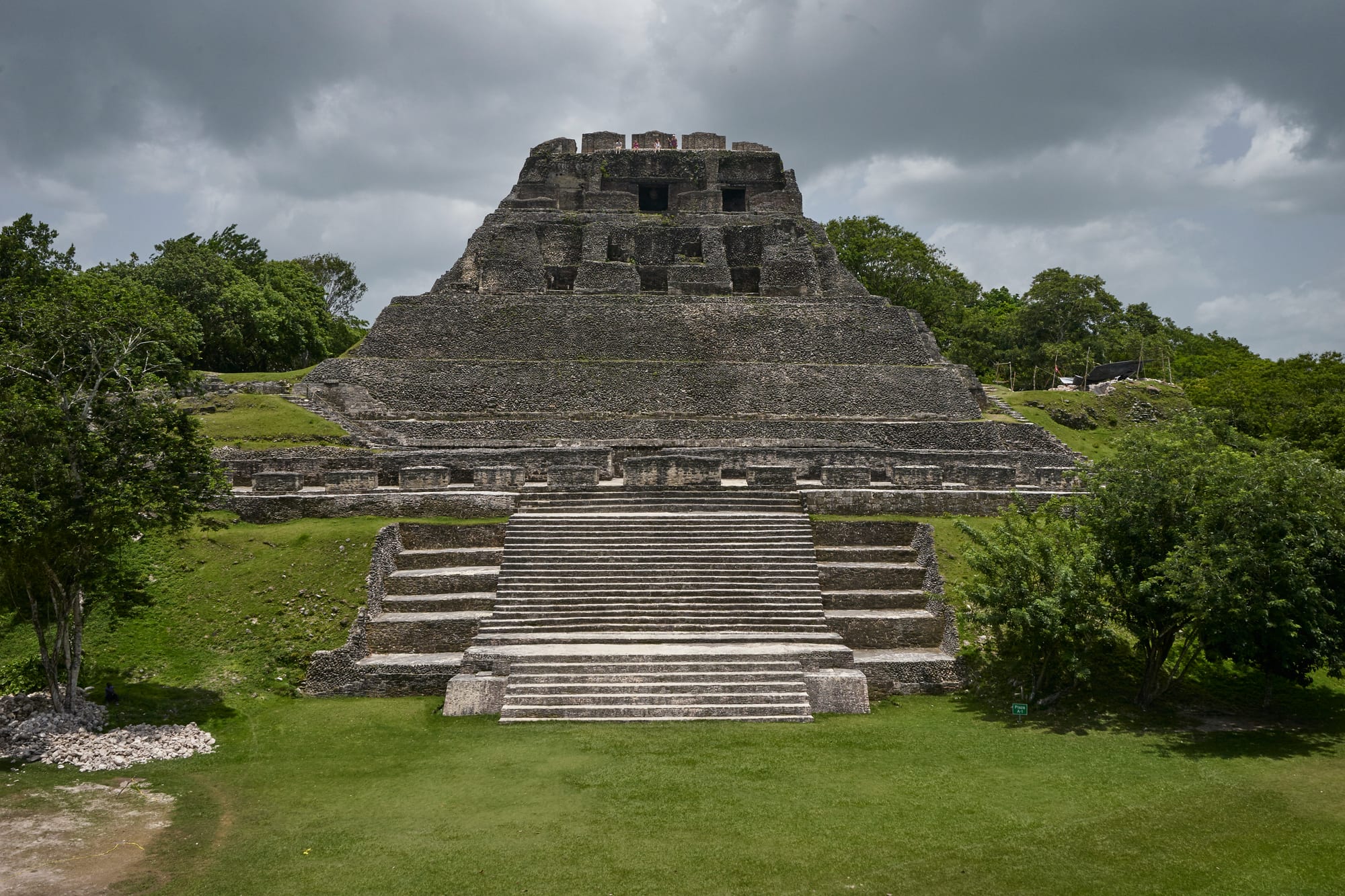 A large restored stone temple-pyramid with a decorated frieze, jungle behind