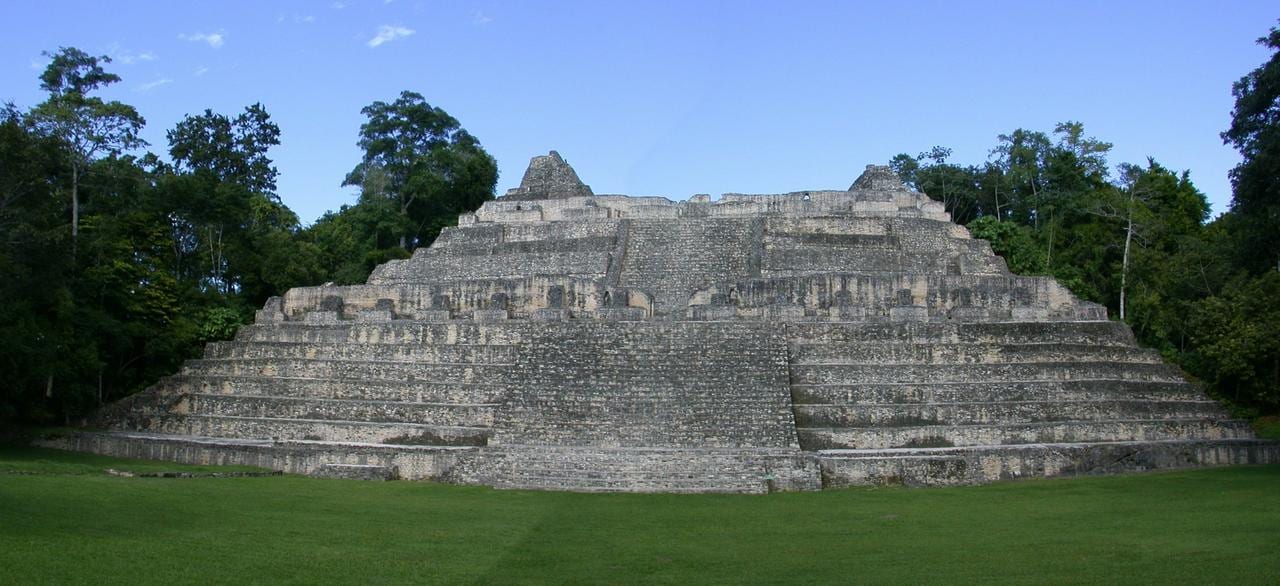 A tall stepped stone pyramid rising above the rainforest canopy