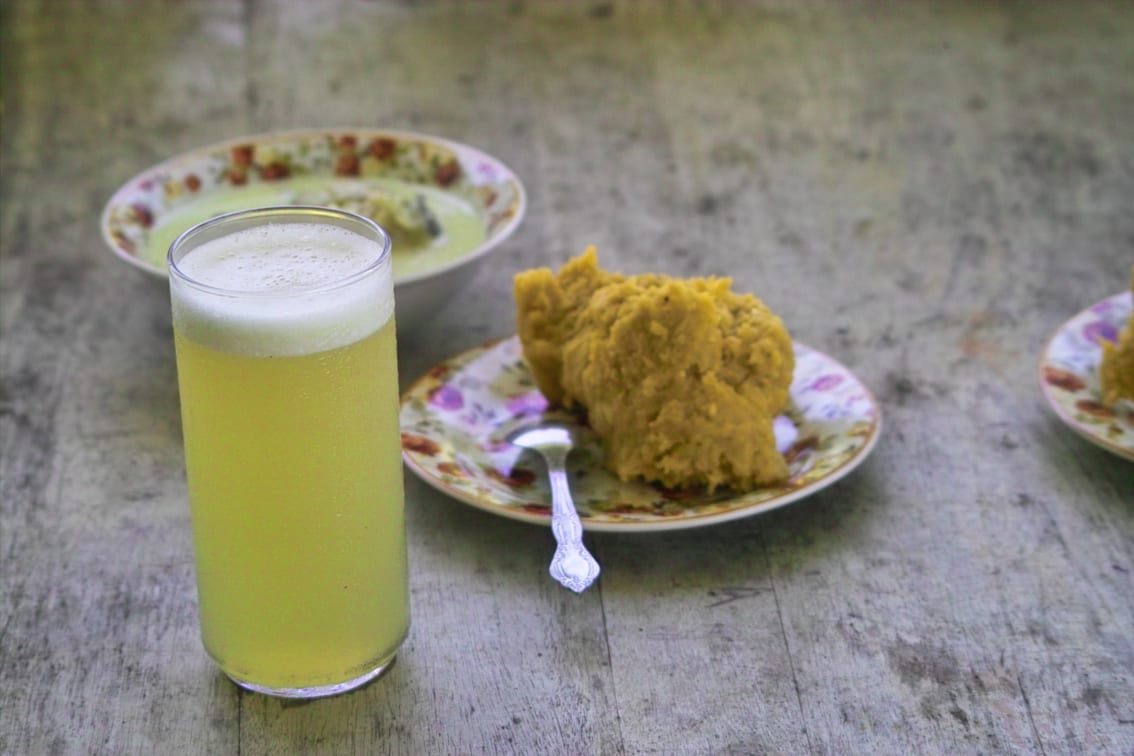 A bowl of mashed plantain beside fish in a light broth