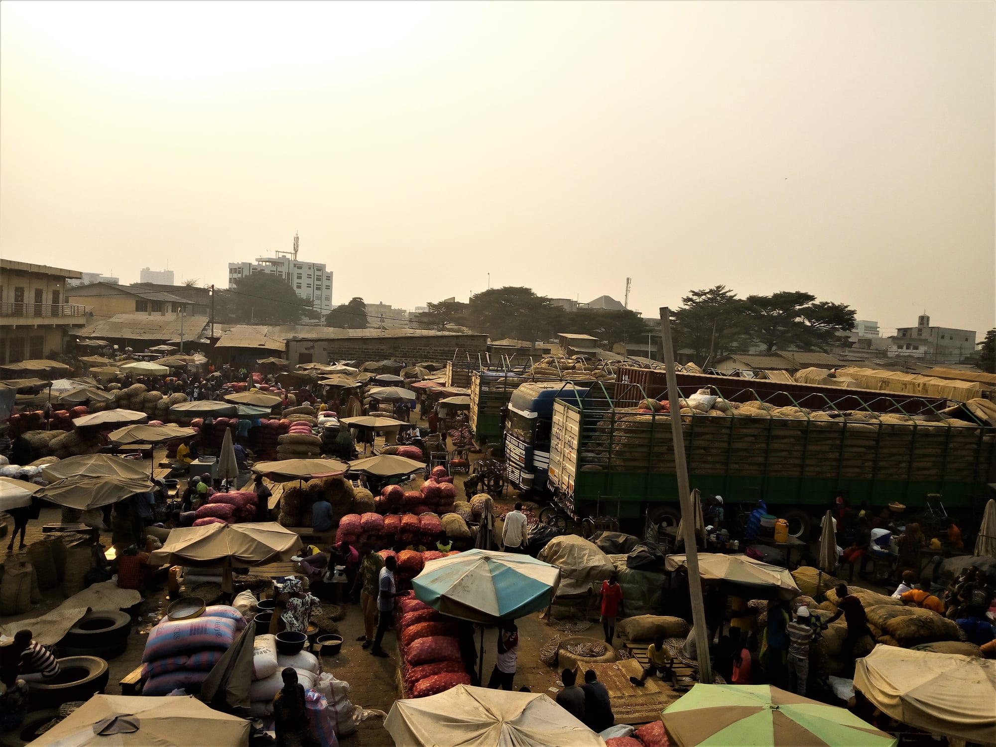 A wide panoramic view over a sprawling open-air market beside a lagoon