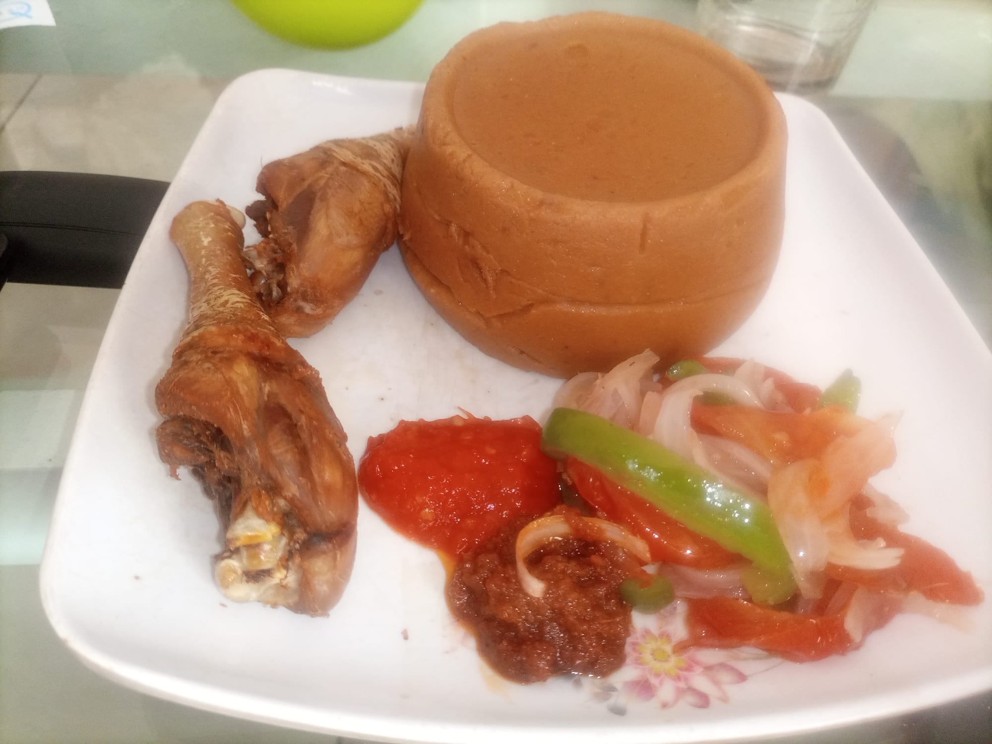 A bowl of thick red-orange corn dough beside a bowl of tomato-based sauce