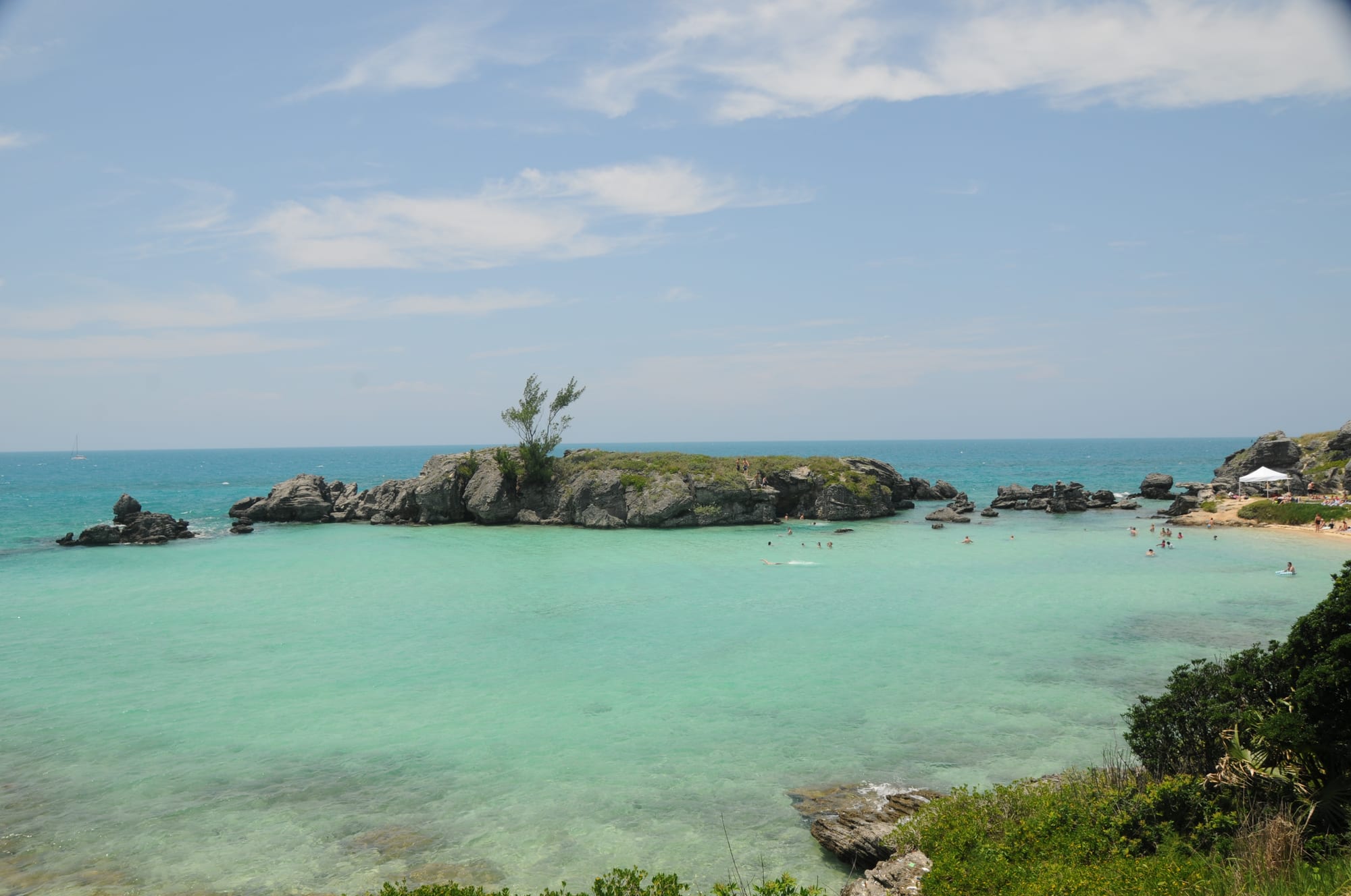 A small cove enclosed by wind-eroded limestone rock stacks, clear shallow water