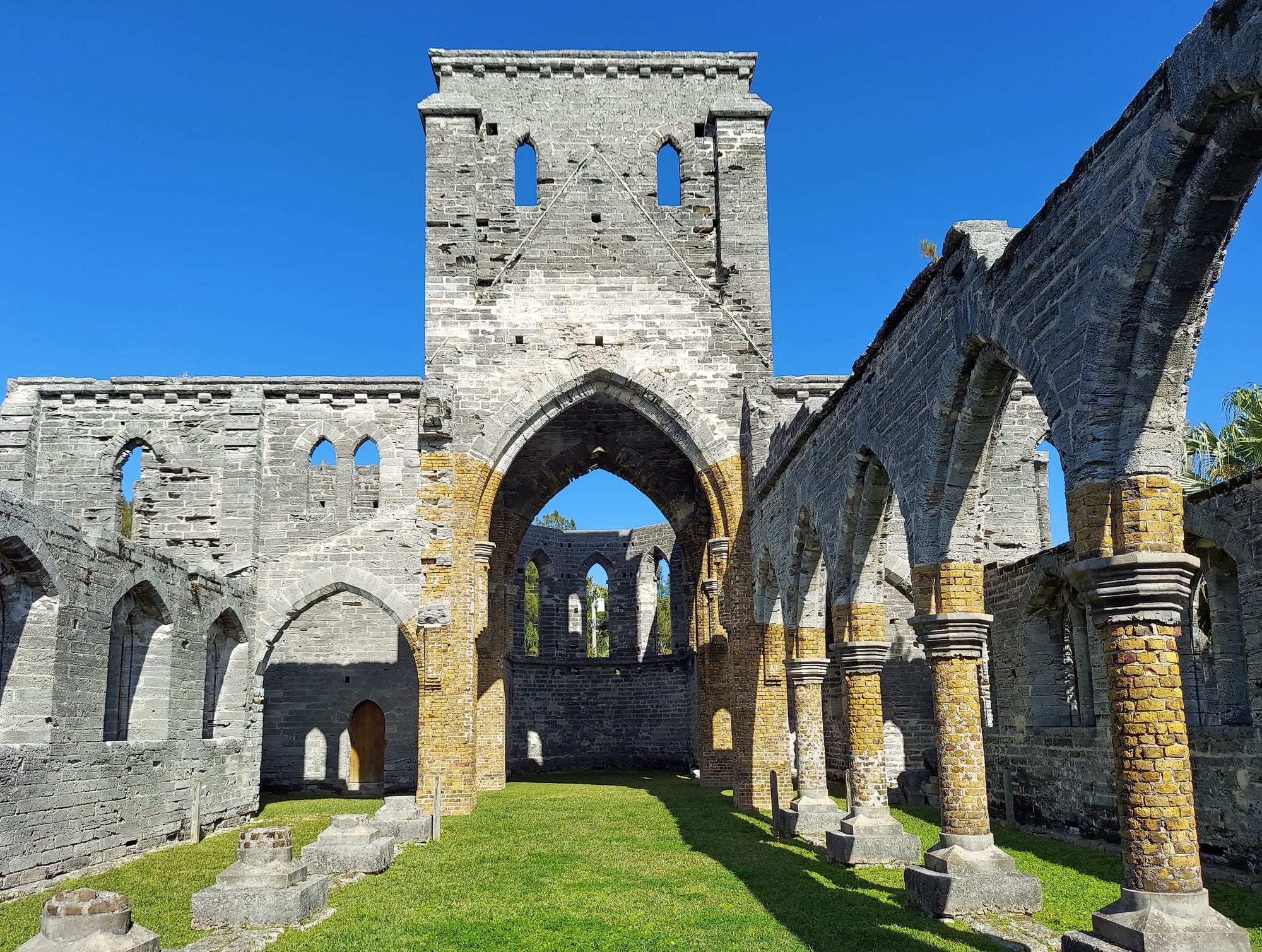 The roofless stone shell of a Gothic church, arches and windows open to the sky, ivy on the walls