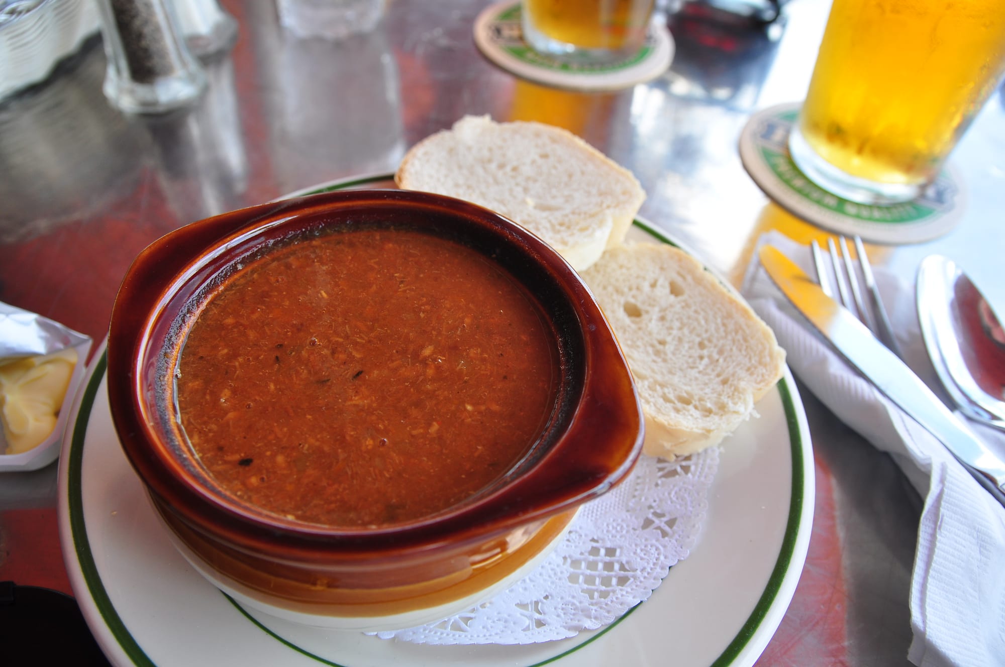 A bowl of dark reddish-brown fish chowder with a swirl visible on the surface