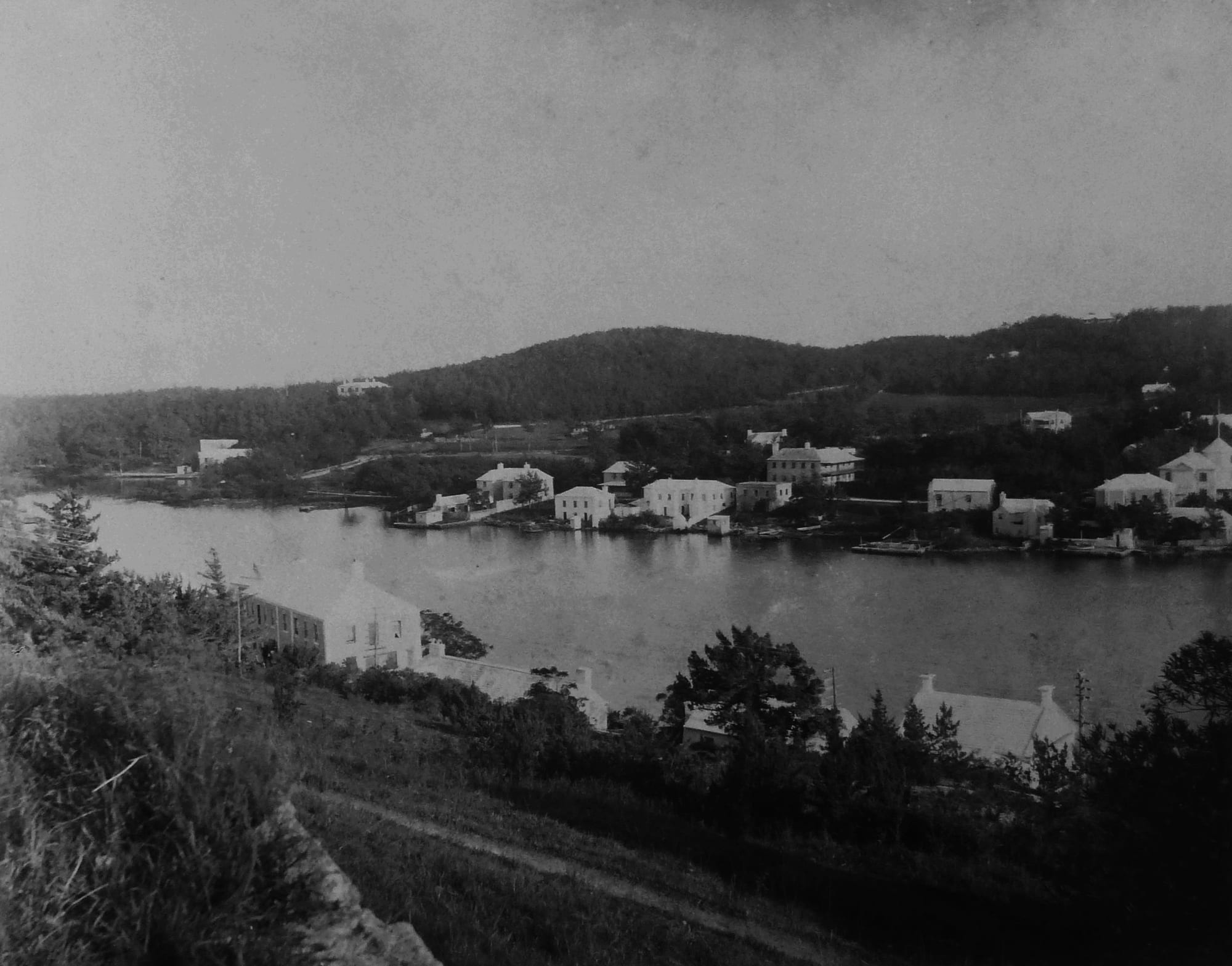 A 1904 photograph looking down over a calm harbour dotted with sailing boats and green islands