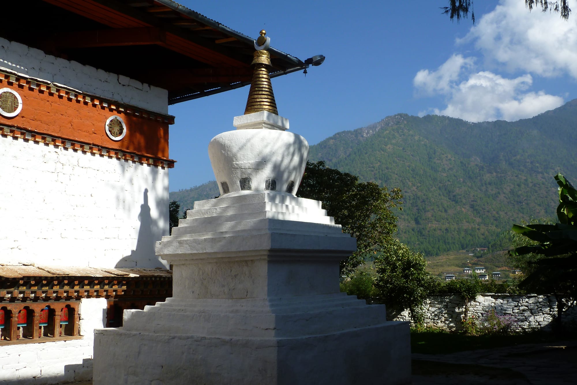 A small whitewashed temple with a golden roof finial and a courtyard of prayer wheels