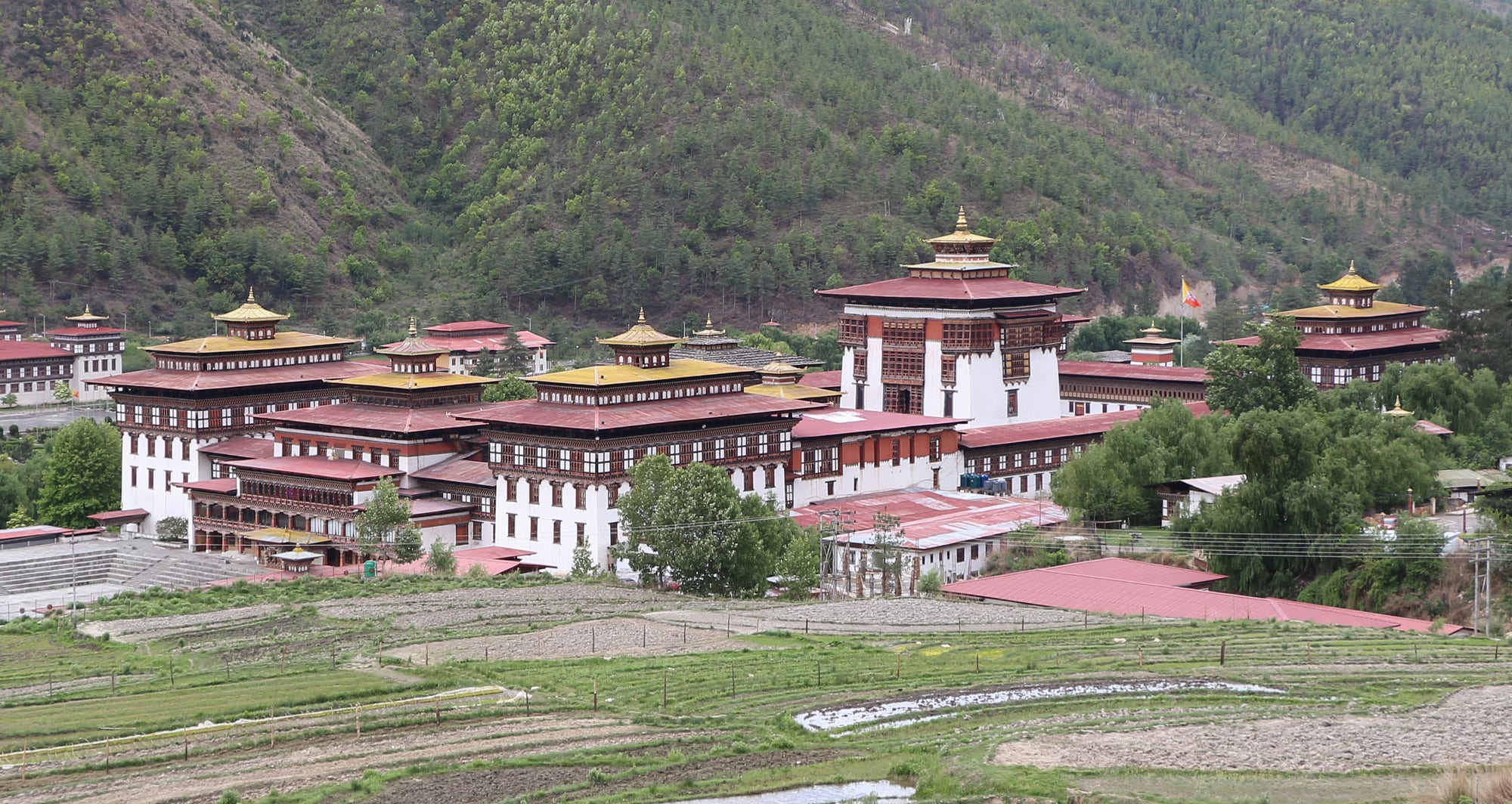 A long white fortress with golden-roofed towers behind manicured lawns