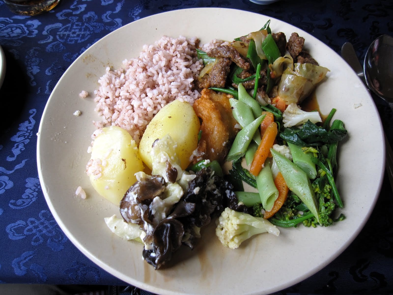 Small dishes of potatoes, mushrooms, greens and red rice arranged together