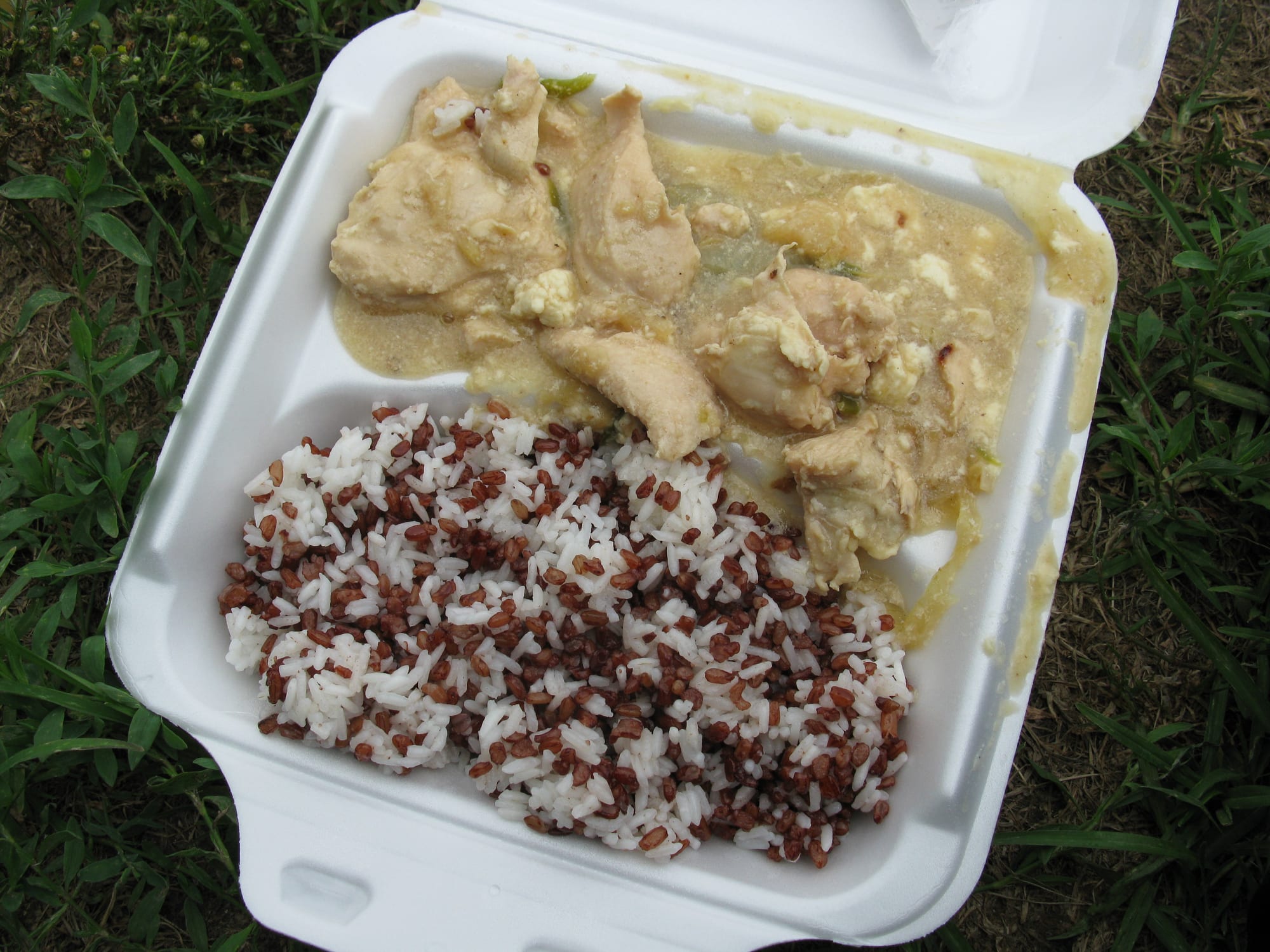 A plate of minced chicken in a reddish sauce beside a mound of red rice
