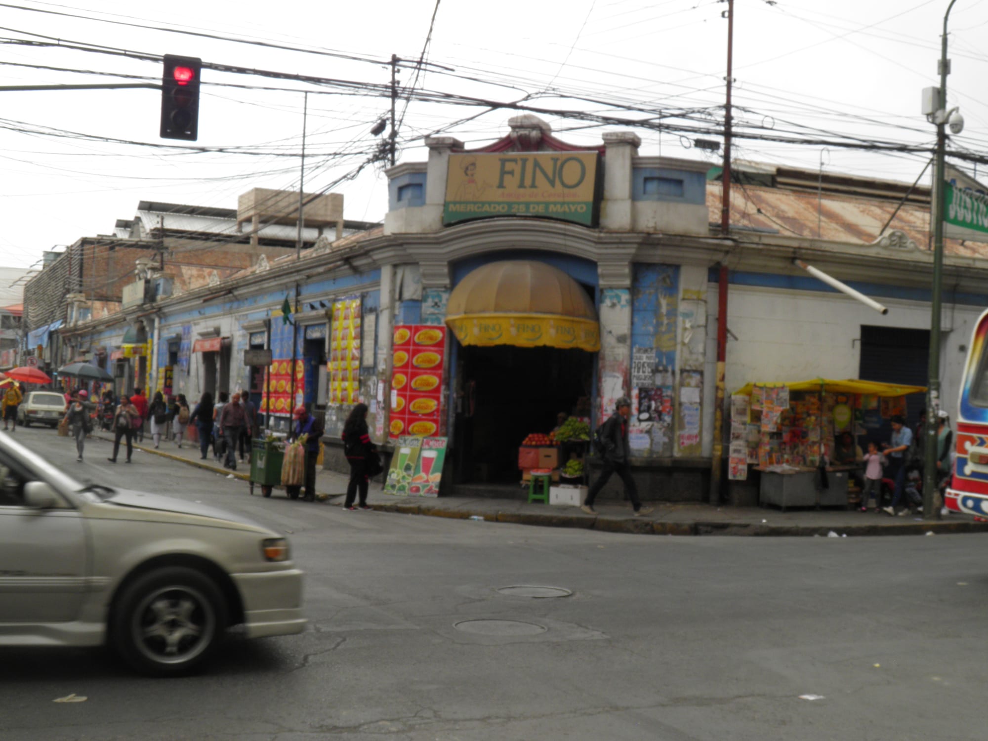 The entrance to a covered market in Cochabamba, with fruit and vegetable stalls and pedestrians on the street outside