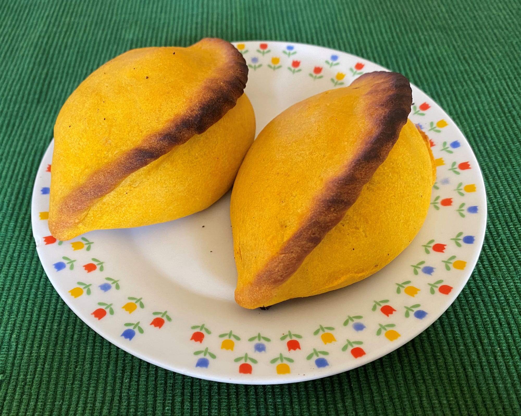 Several golden, crimped pastries filled with a stew visible where one has been cut open