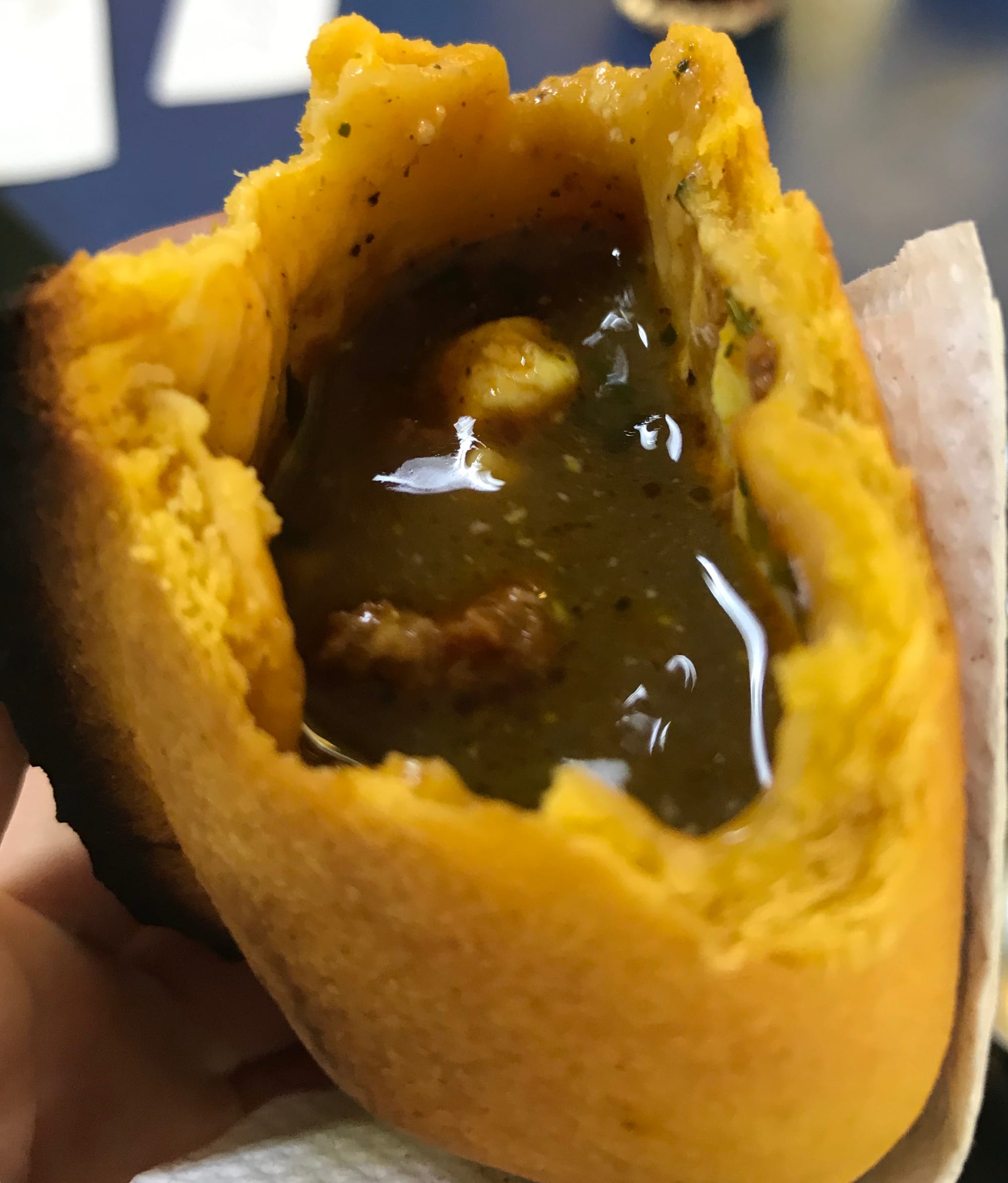 A cut-open pastry showing a juicy, sauce-filled stew interior with visible chunks of meat and potato