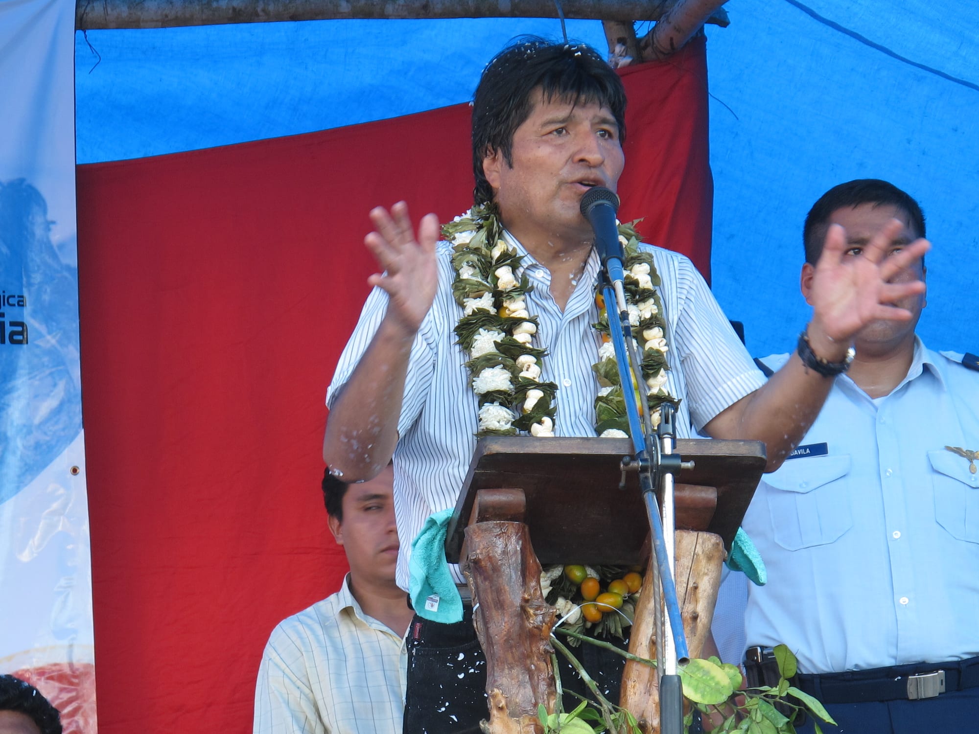 Evo Morales in a garland of coca leaves and flowers speaking to a crowd of rural supporters