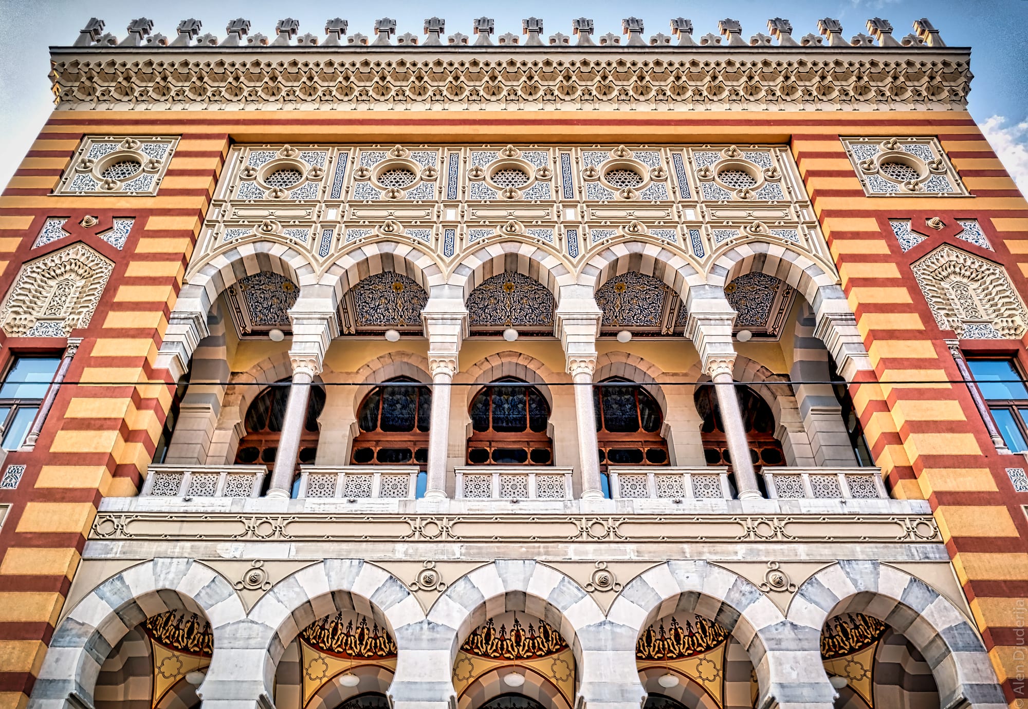 A striped neo-Moorish building with a grand arched façade, lit up against a dark sky
