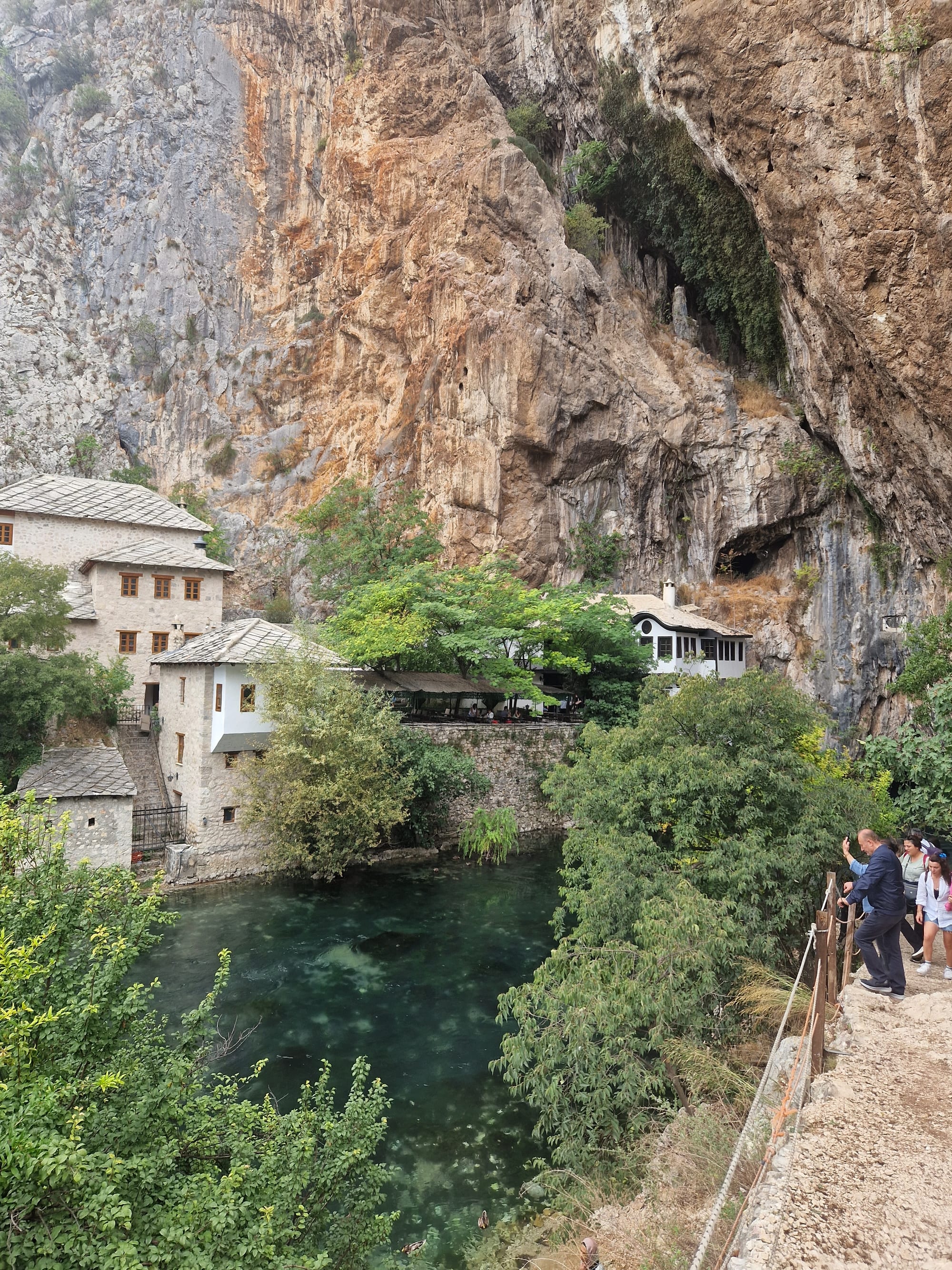 A white Ottoman house built against a huge cliff at the point where a river emerges from a cave