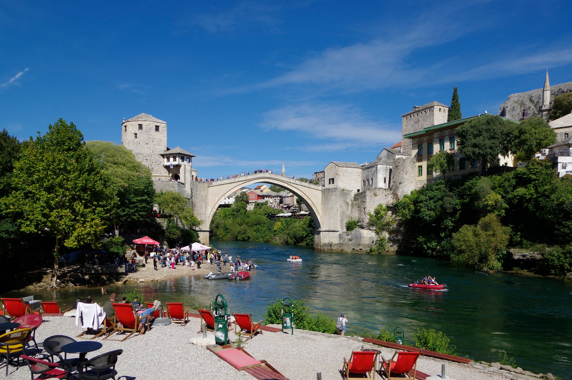 A steep humpbacked stone bridge crowded with people, green river below