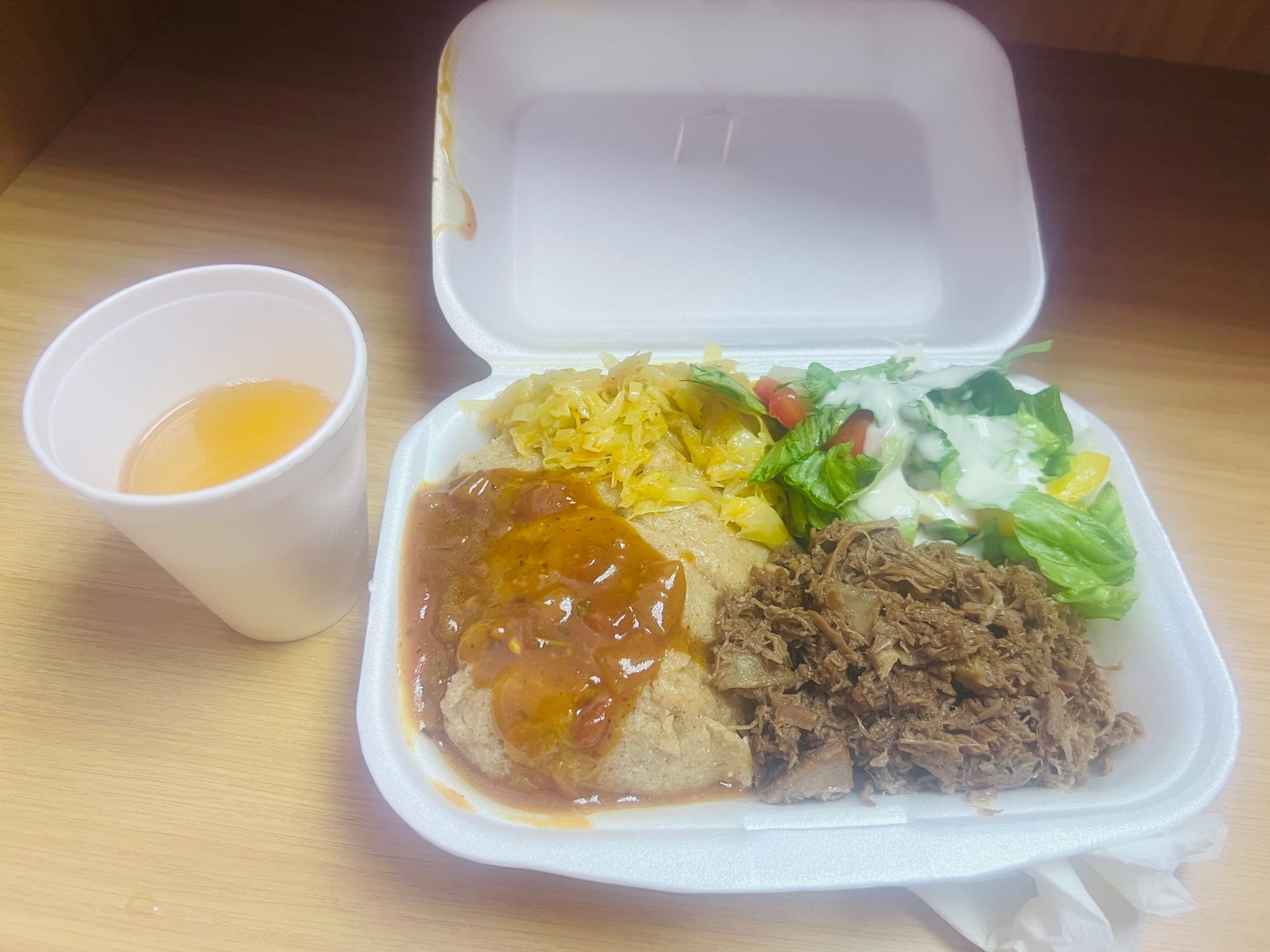 A plate with a mound of grey-white sorghum porridge beside pounded shredded beef