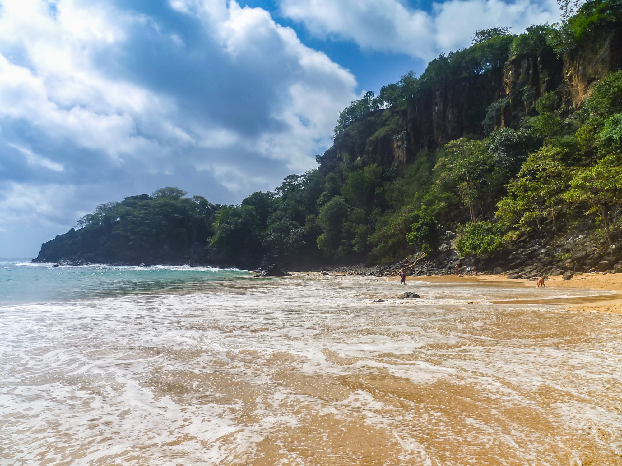 A crescent beach at the foot of jungle-topped cliffs, brilliant turquoise water offshore