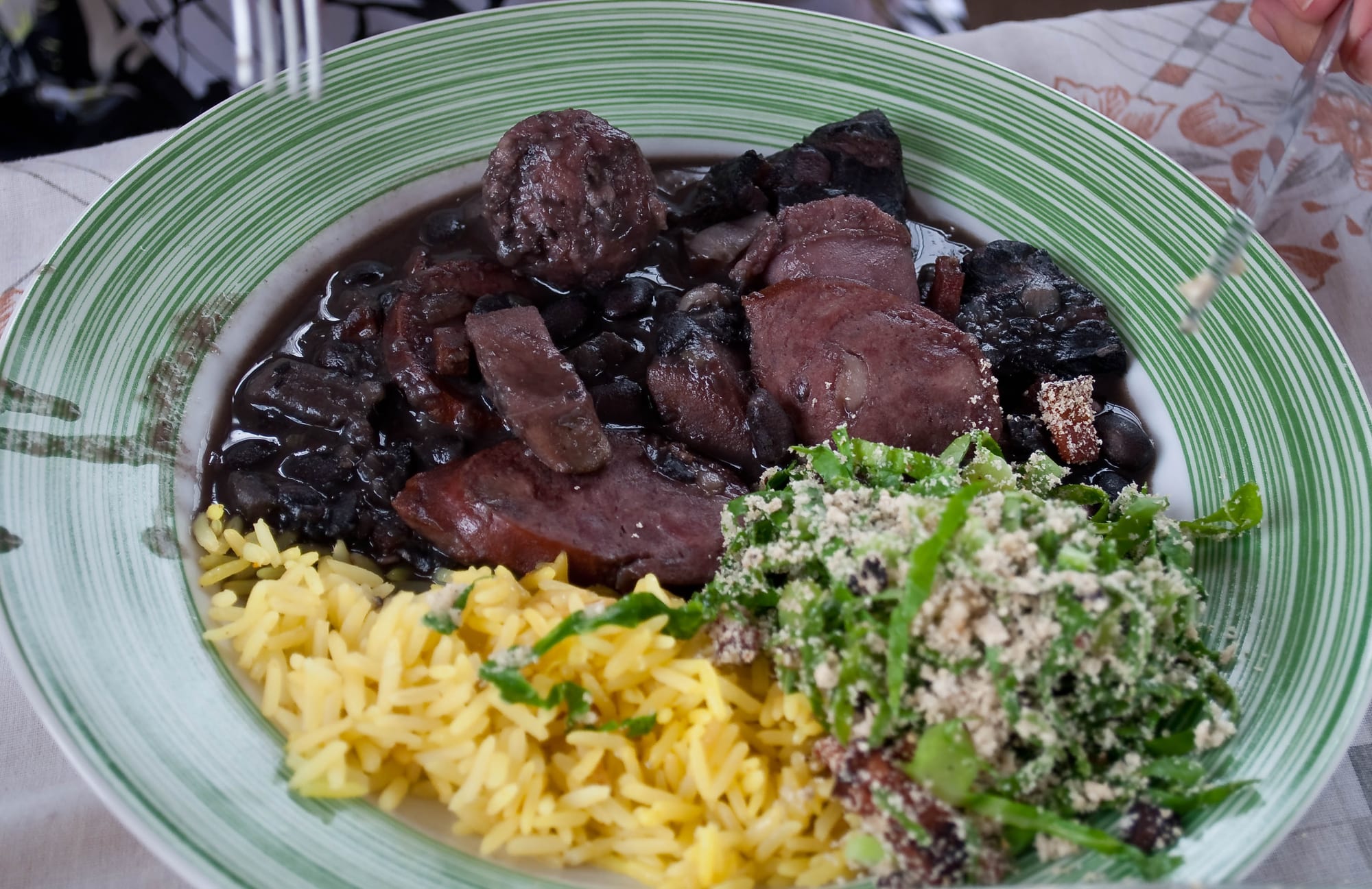 A dark, rich black bean and pork stew served with rice, greens and orange slices