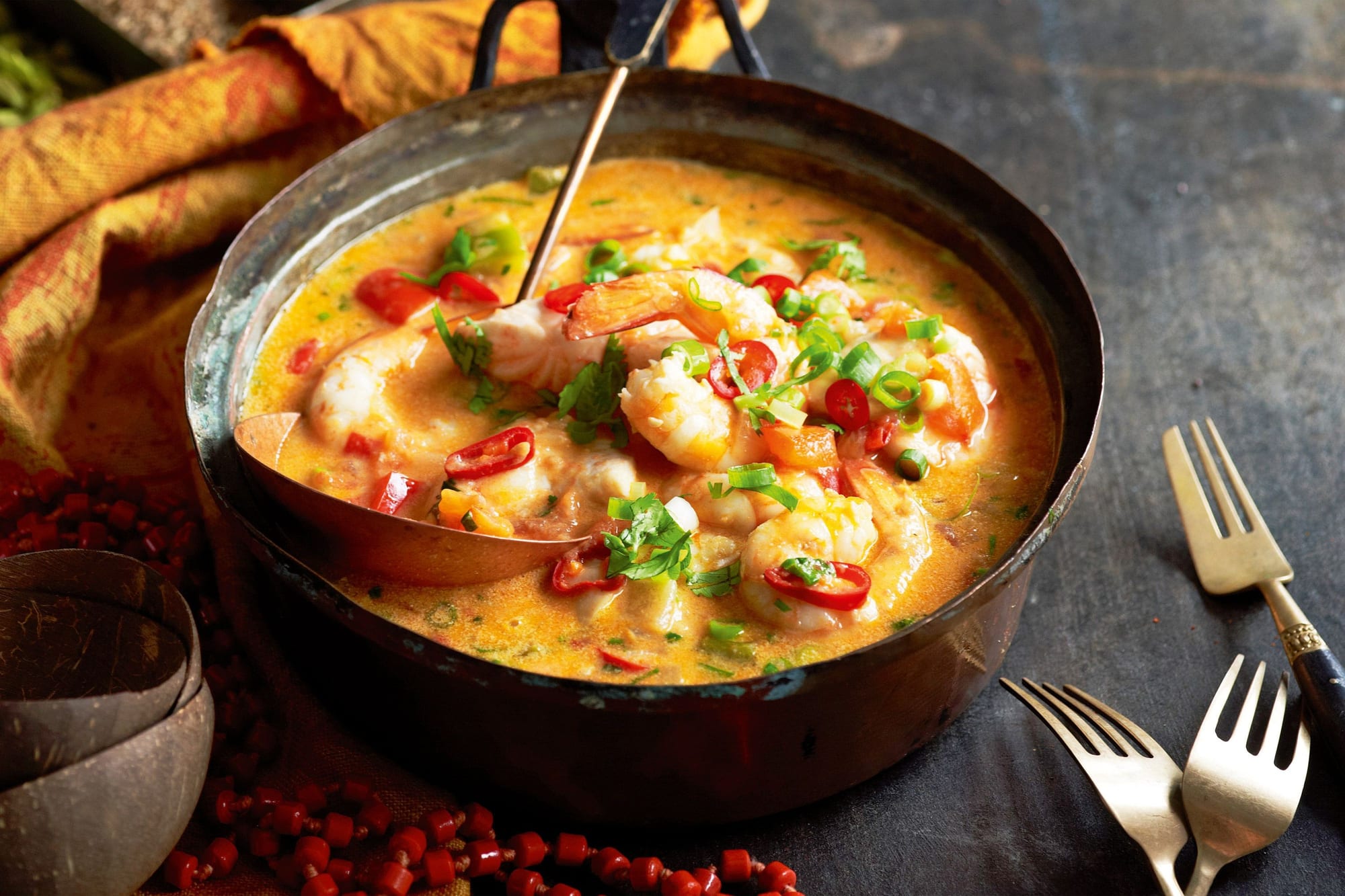 An orange, coconut-and-palm-oil-based fish stew in a clay pot