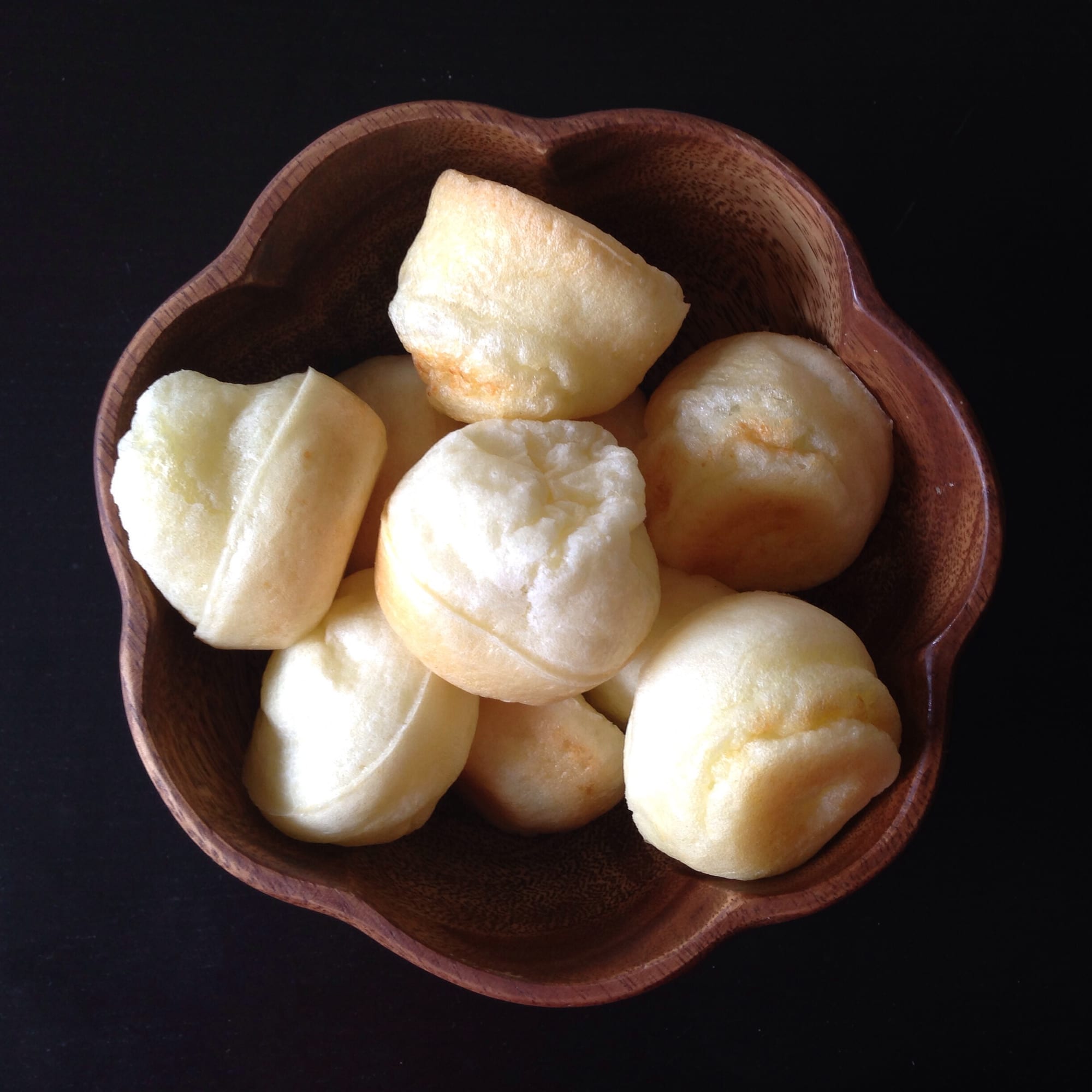 A basket of small, golden, round cheese bread rolls
