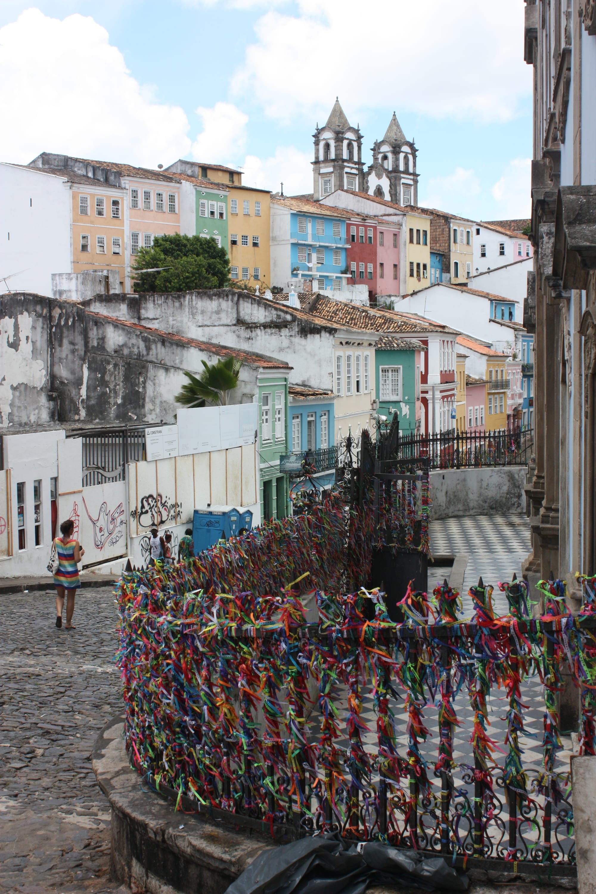 A steep cobbled square lined with tall pastel baroque townhouses and a blue-and-white church