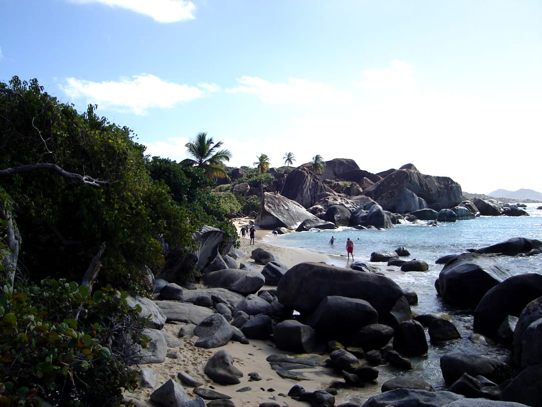 A sunlit passage between huge smooth boulders leading to turquoise sea
