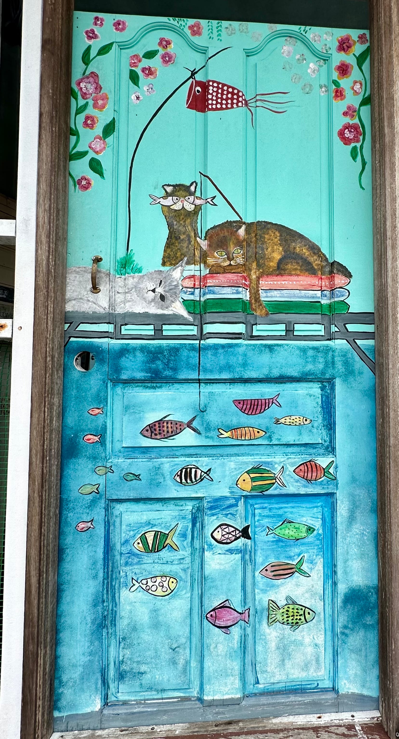 A house door in Kampong Ayer hand-painted with cats, fish and flowers in blue and green