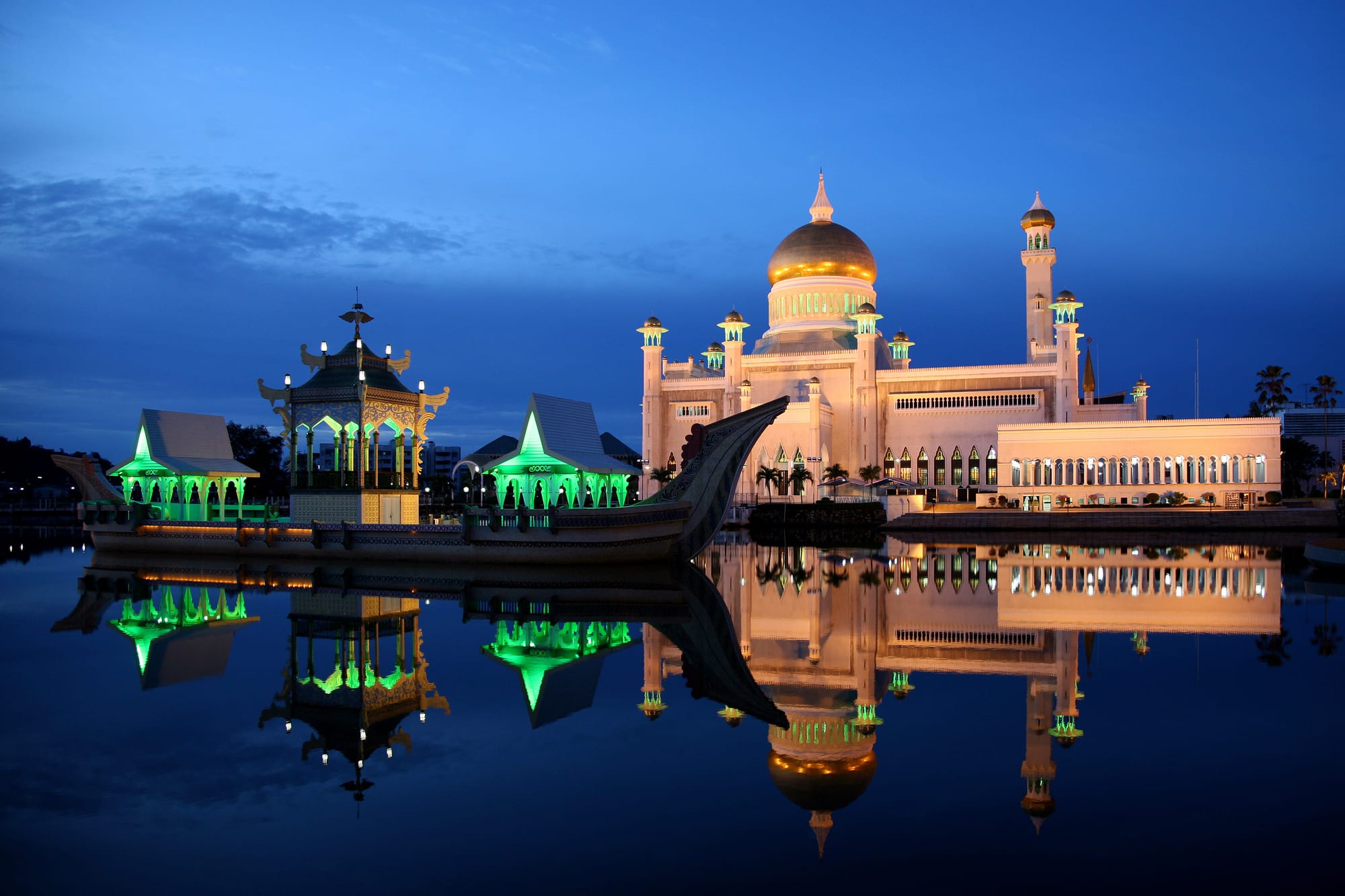 A grand white-and-gold mosque behind palms and a fountain, against a blue sky